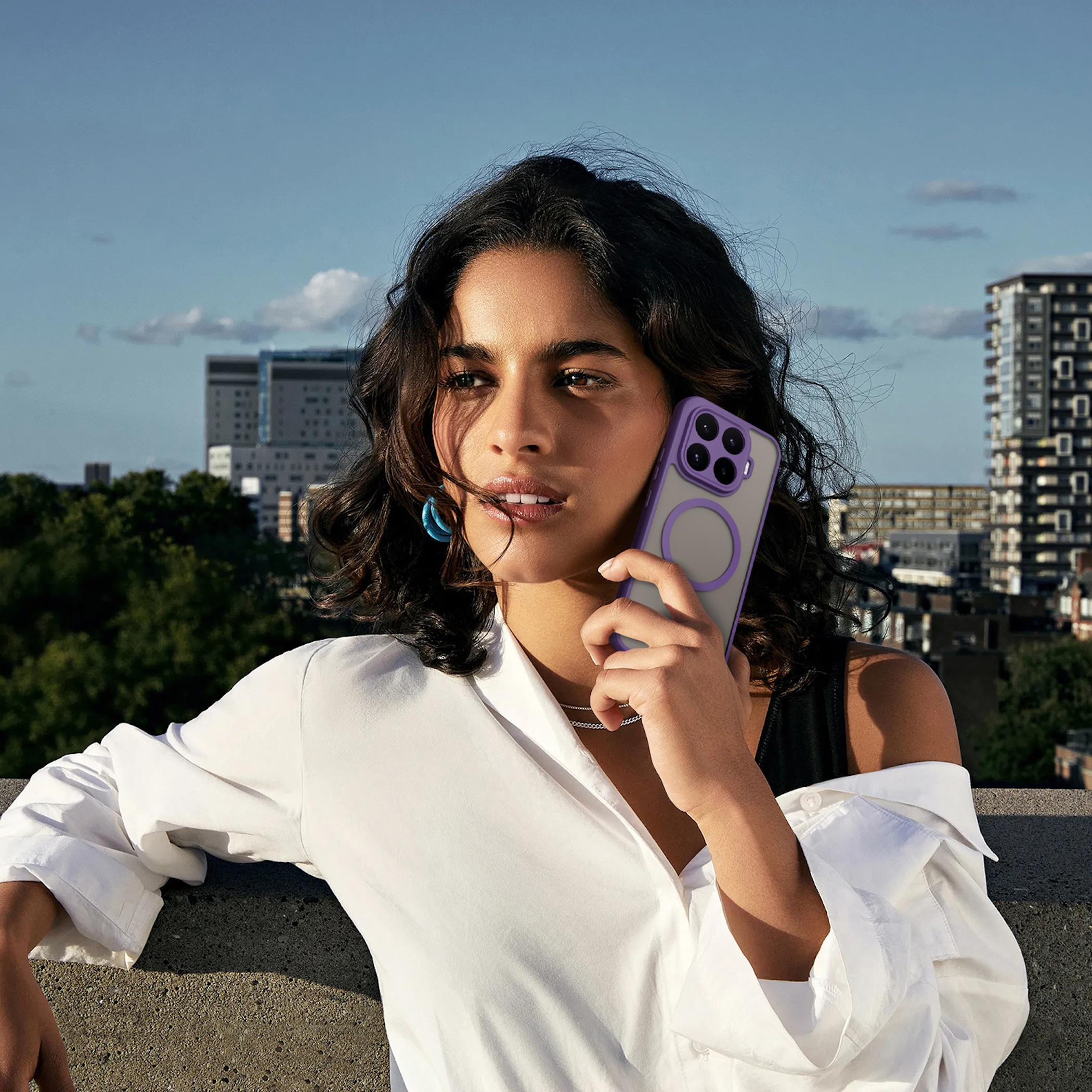 Frau mit Handy auf Dach mit Stadt im Hintergrund.
