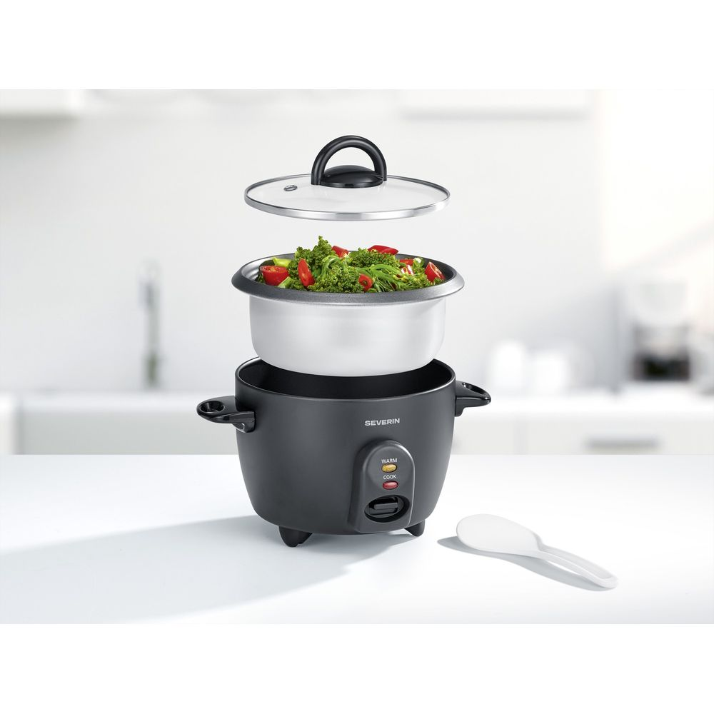 Una cuociriso nera con coperchio aperto, piena di verdure e riso.