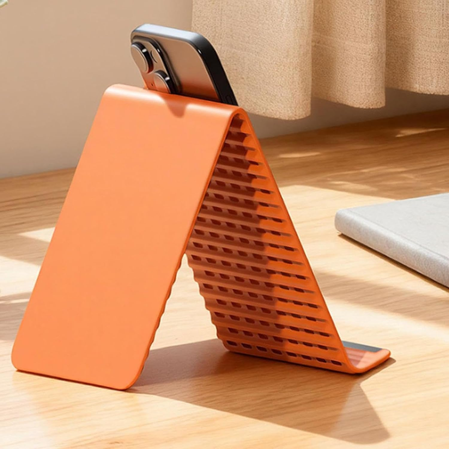 Ein orangefarbener Handyhalter in dreieckiger Form, der ein Smartphone hält.