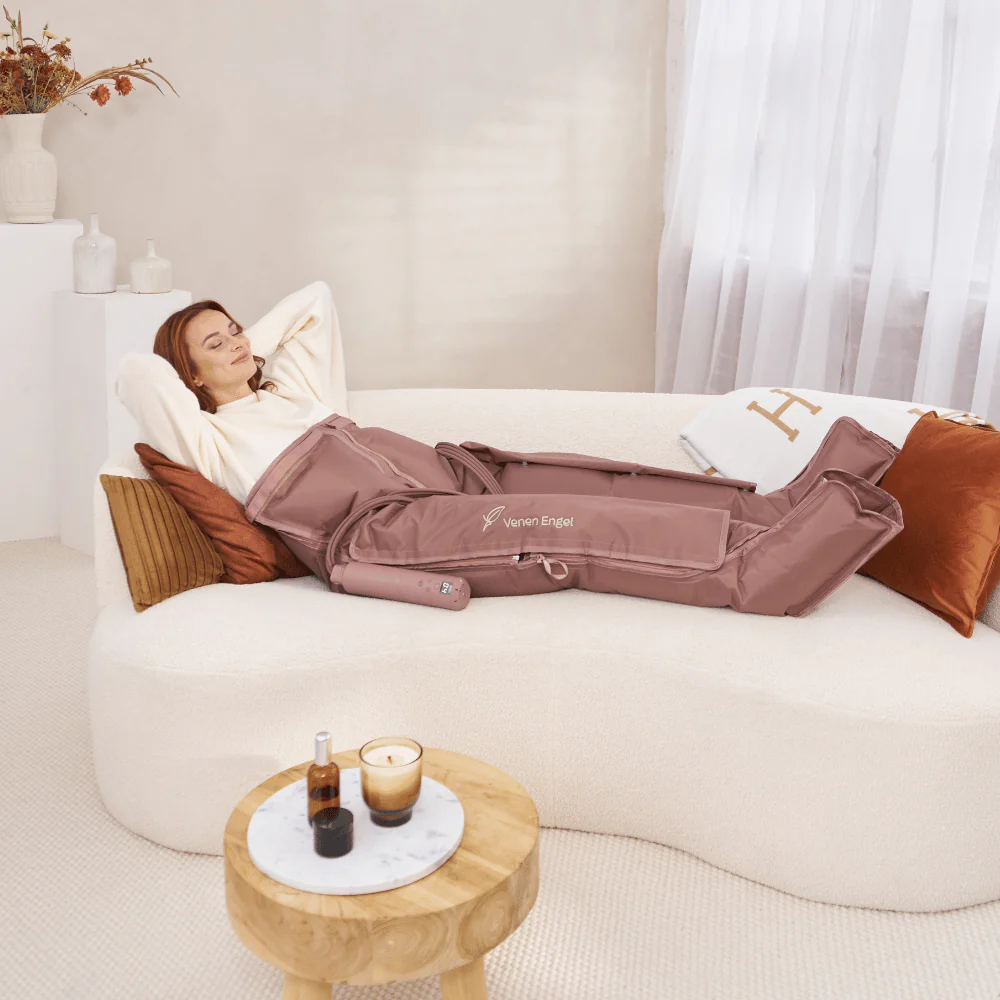 Femme sur canapé avec bottes de compression, allongée détendue.