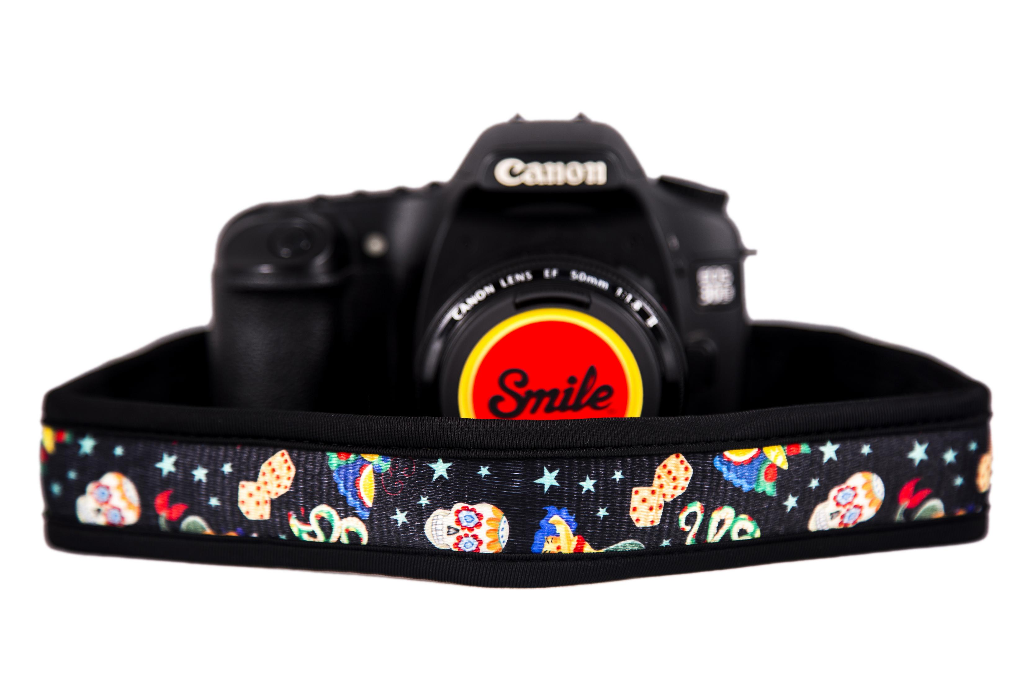 Una fotocamera Canon nera con tracolla colorata con teschi.