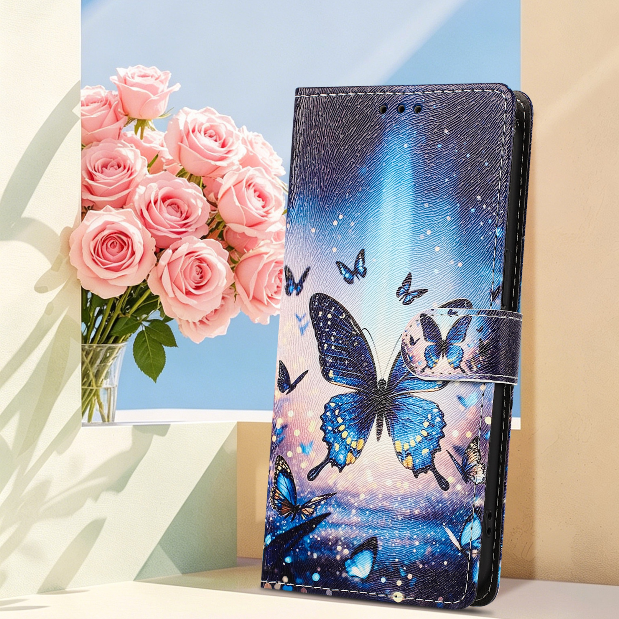 Ein blaues Handycover mit Schmetterlingsmotiv neben rosa Rosen in einer Vase.