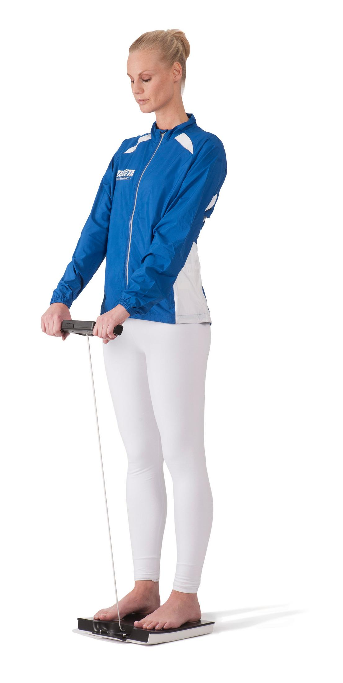 Donna su bilancia, tiene maniglia, indossa giacca blu e pantaloni bianchi.
