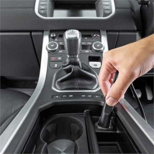 Mano inserisce un dispositivo nero nell'accendisigari dell'auto.