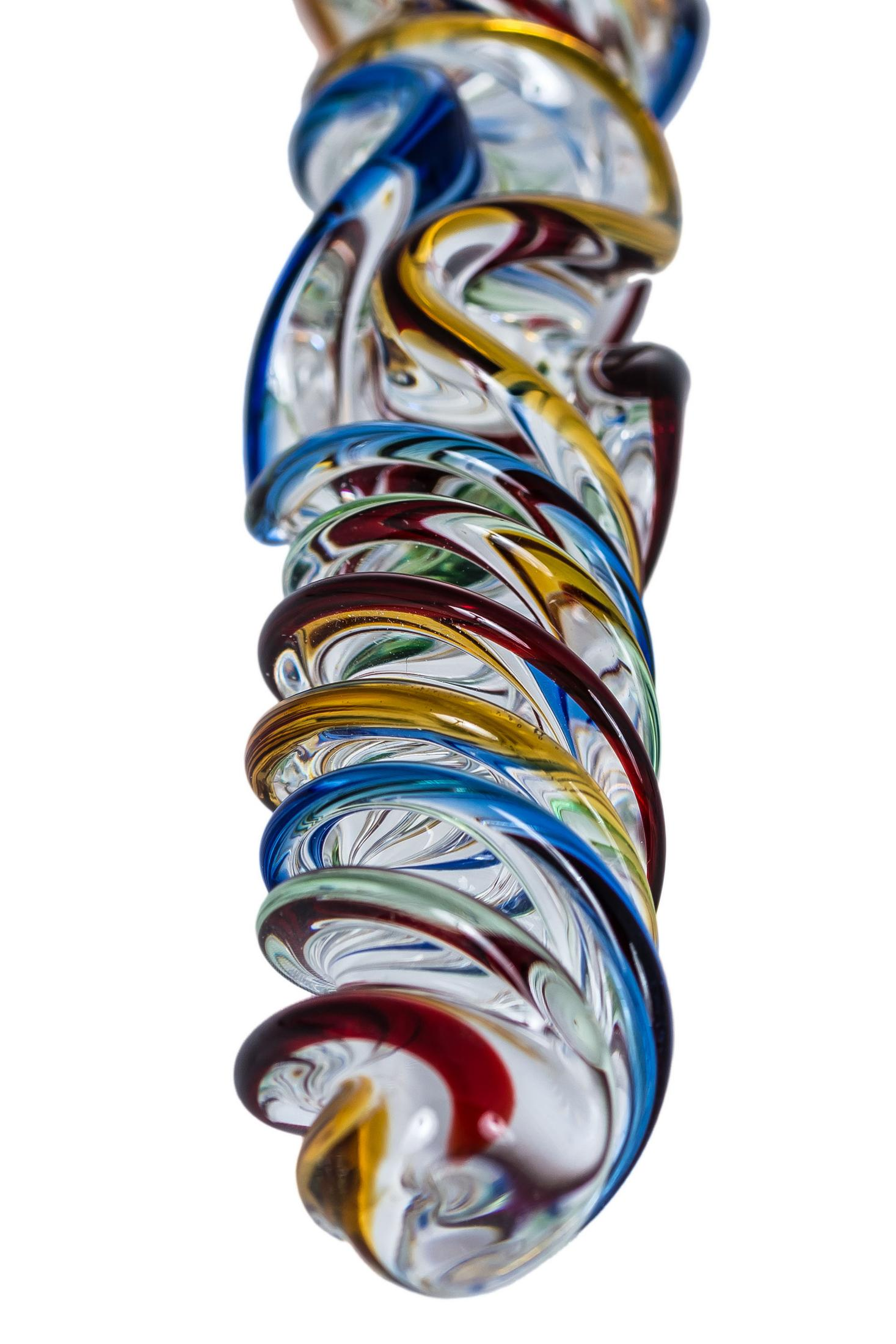 Ein verdrehter Glasstab mit bunten Wirbeln aus Rot, Blau, Grün und Gelb auf weißem Grund.
