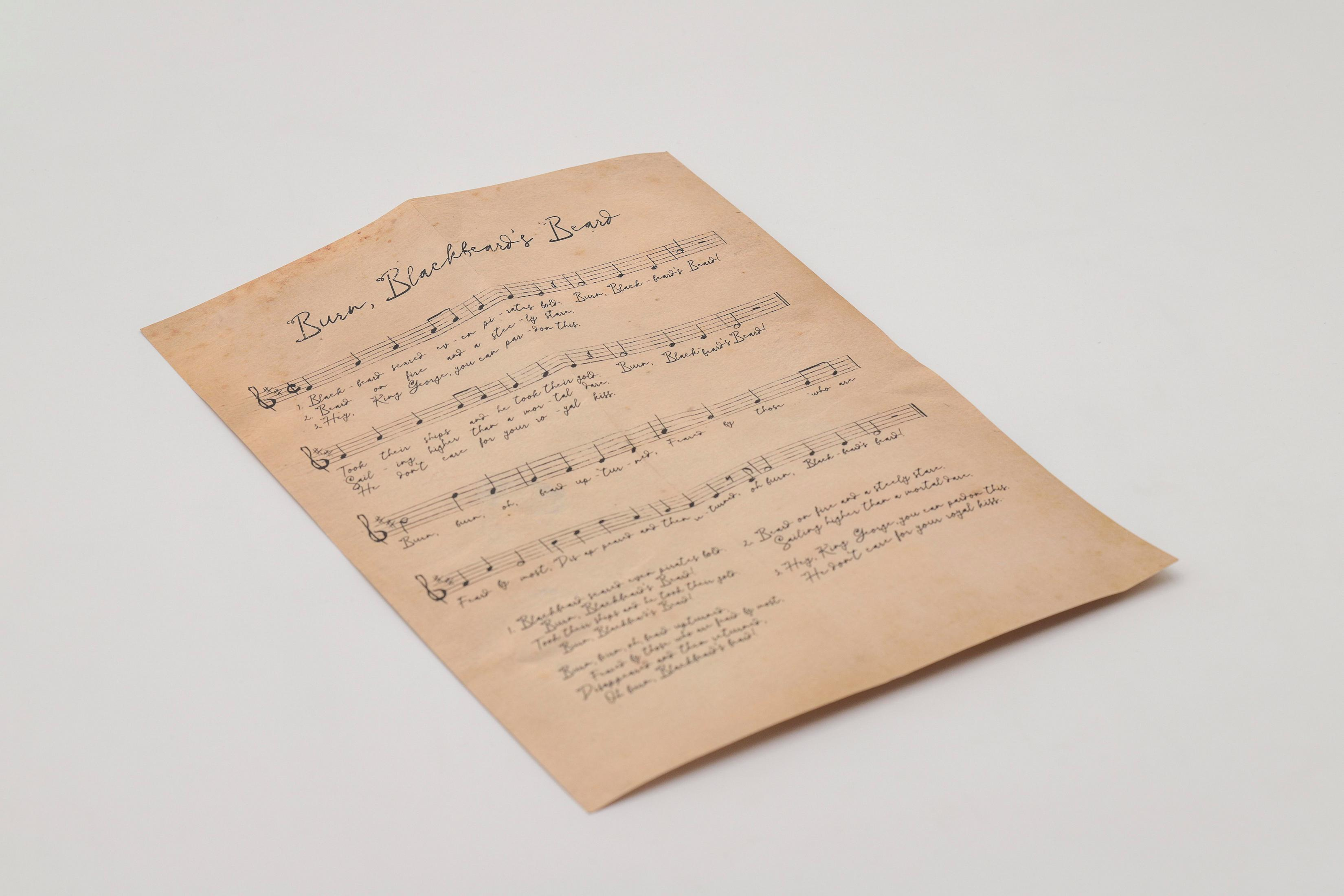 Un foglio musicale ingiallito con testo manoscritto e note musicali.