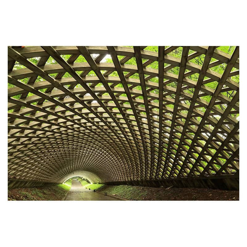 Arcada de túnel de celosía de madera con follaje verde visible a través de las aberturas.
