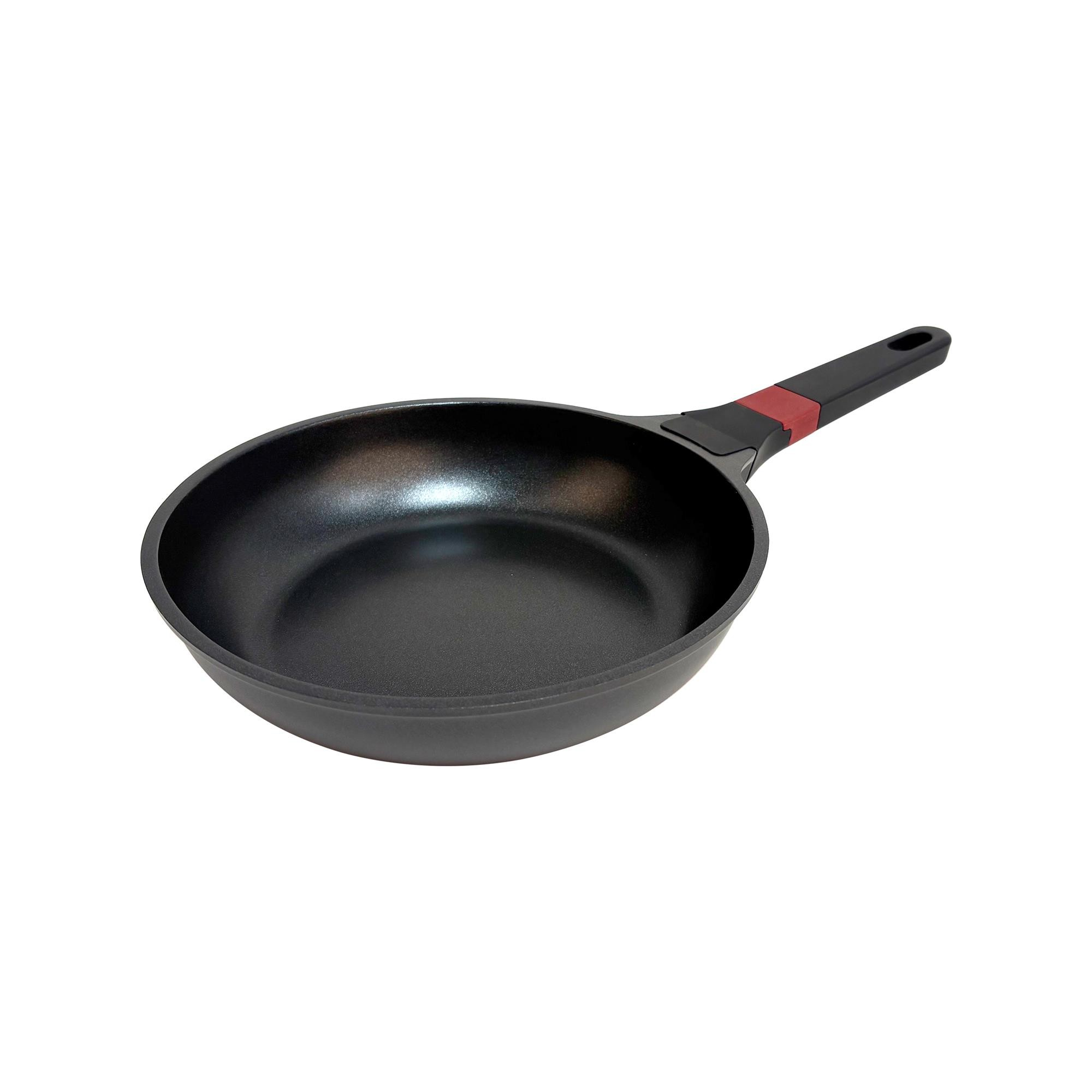 Sartén negra con acento rojo en su mango negro, aislada sobre blanco.