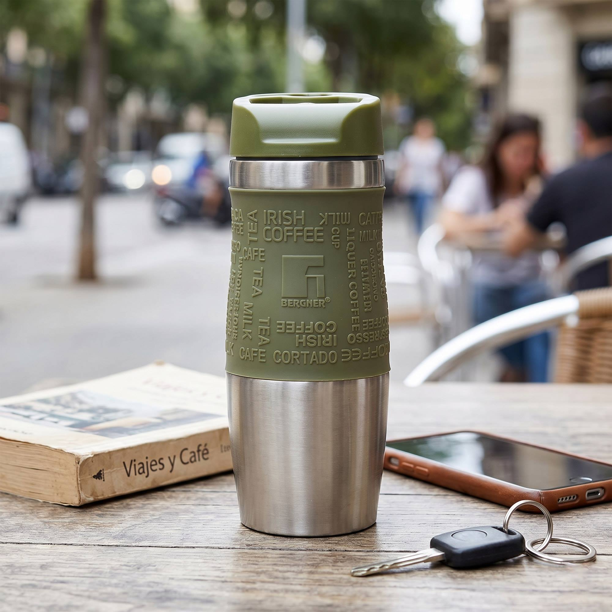 Un termo verde está sobre una mesa de madera con un libro, teléfono y llaves.
