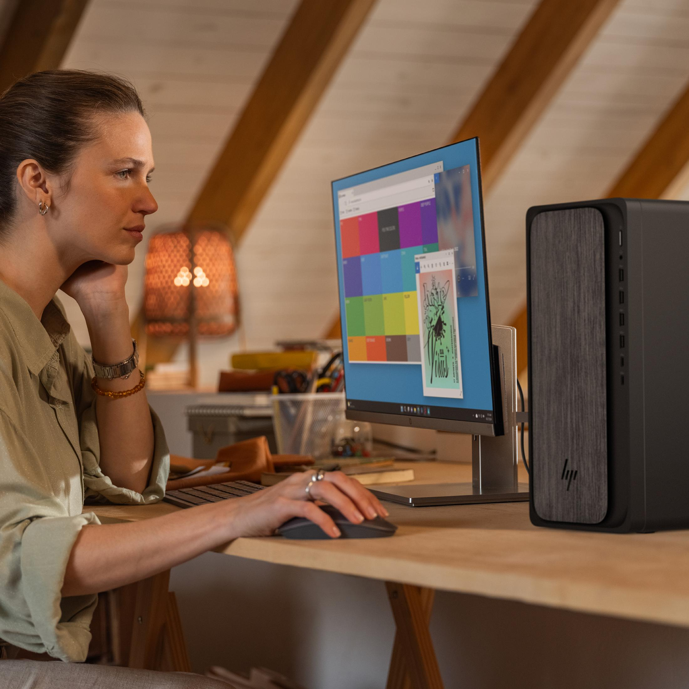 Frau am Schreibtisch benutzt Computer. Bildschirm zeigt Farbpaletten und eine Grafik.