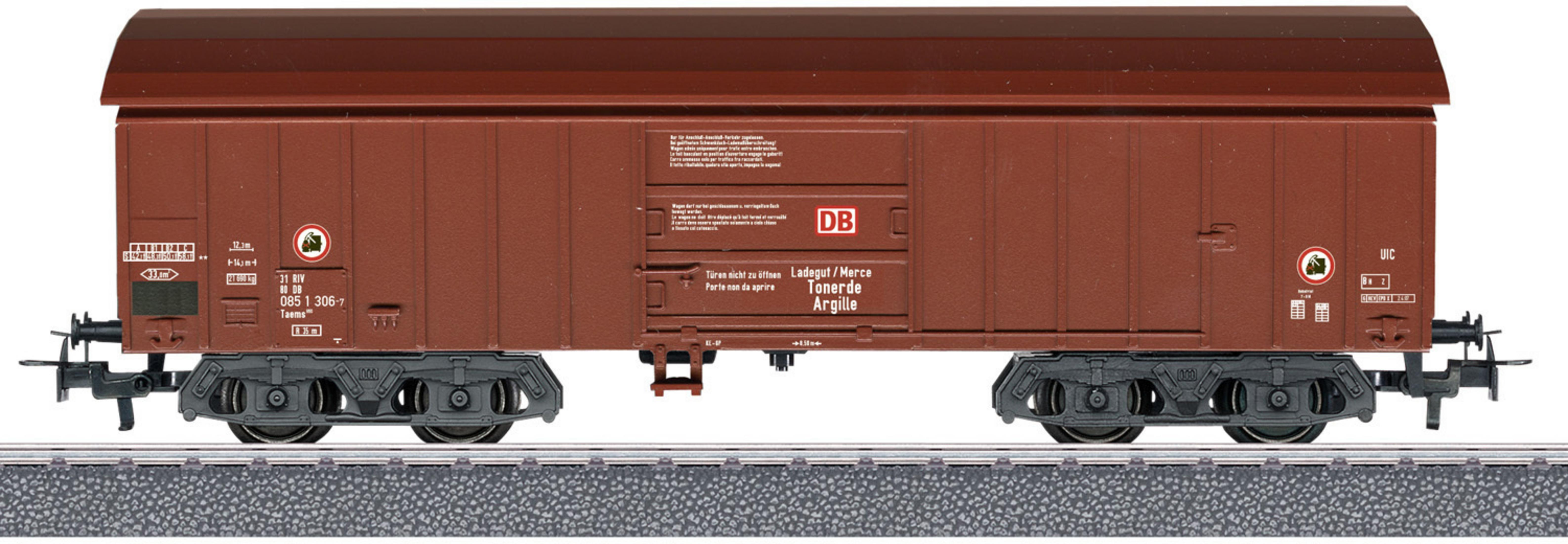 Brauner Güterwaggon der DB mit Beschriftungen und Fahrgestell auf Schienen.
