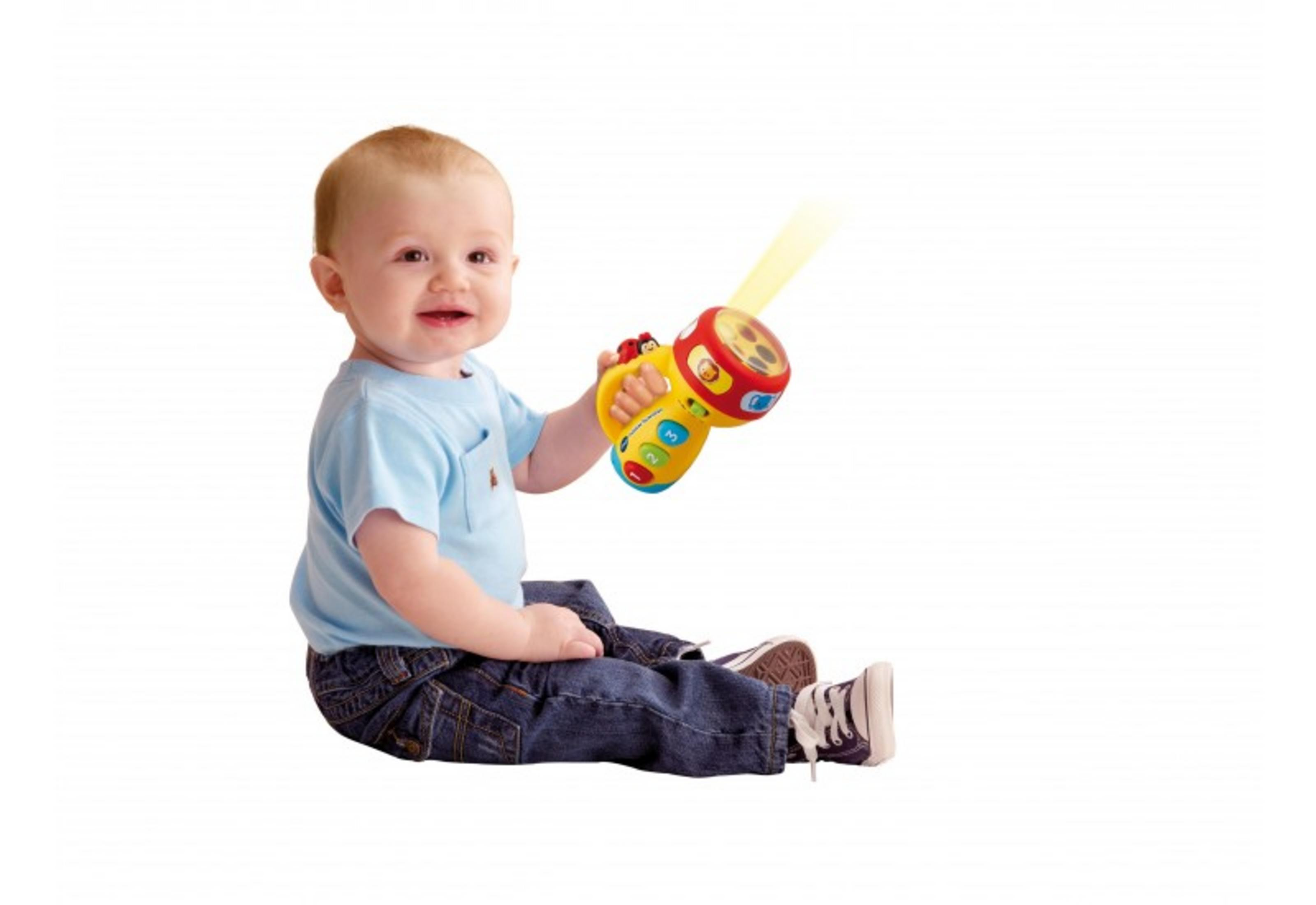 Ein Baby in Jeans und blauem T-Shirt sitzt und hält eine Spielzeug-Taschenlampe.