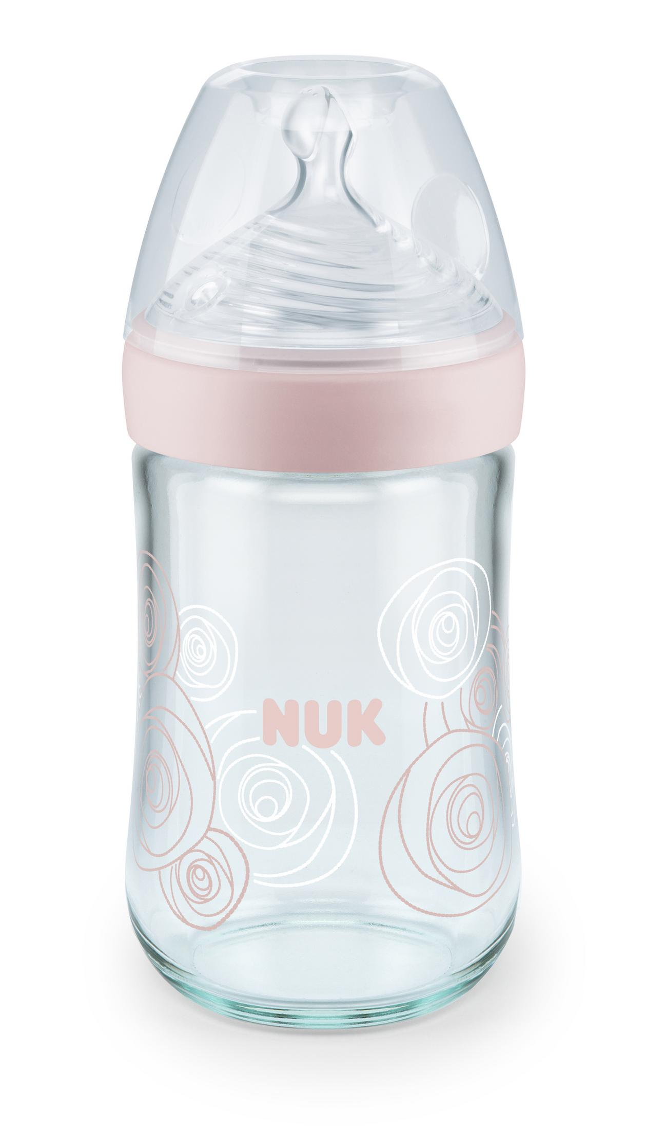 Eine durchsichtige Babyflasche mit rosa Ring und Blumenmuster.
