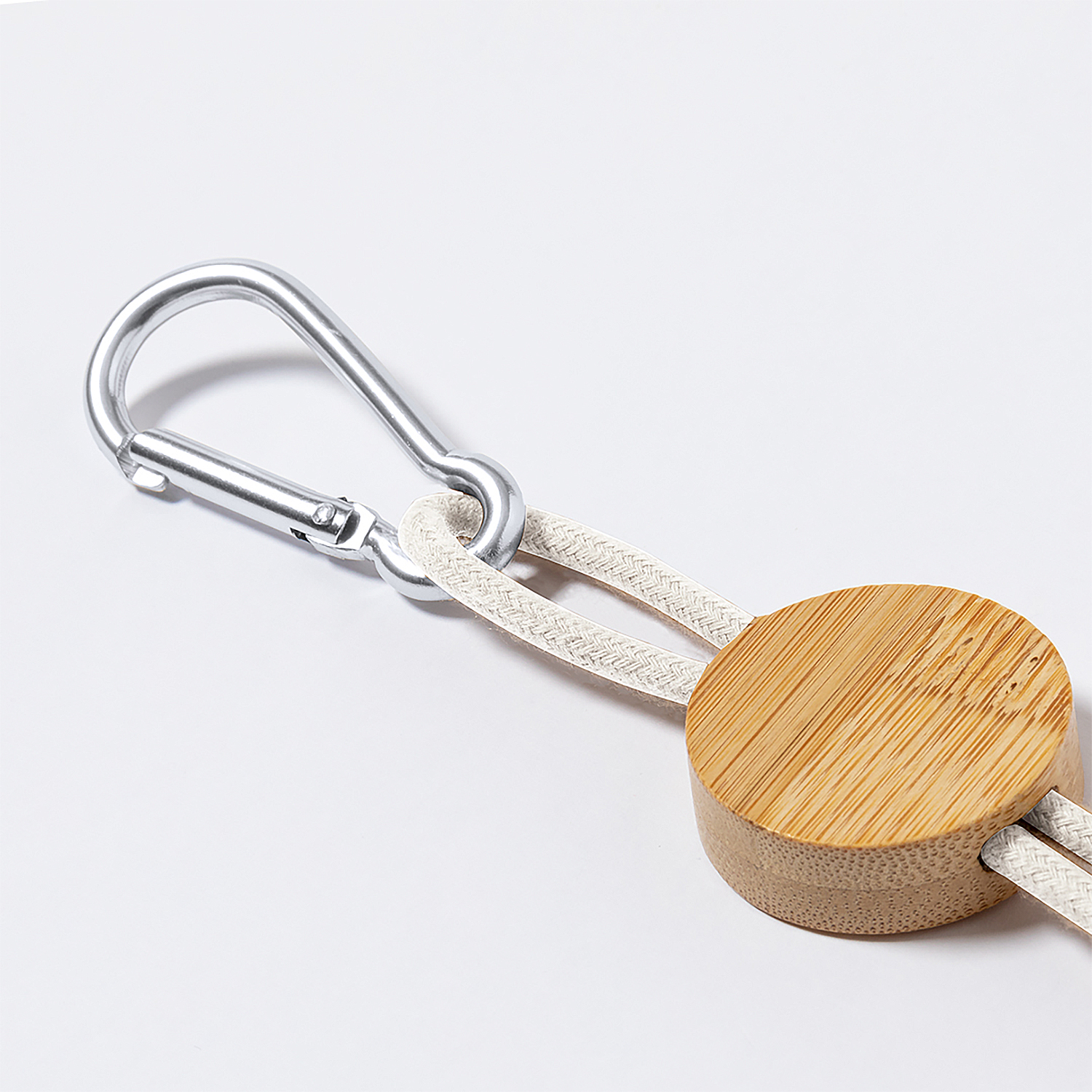 Un moschettone argentato con un disco di legno e corda su sfondo bianco.