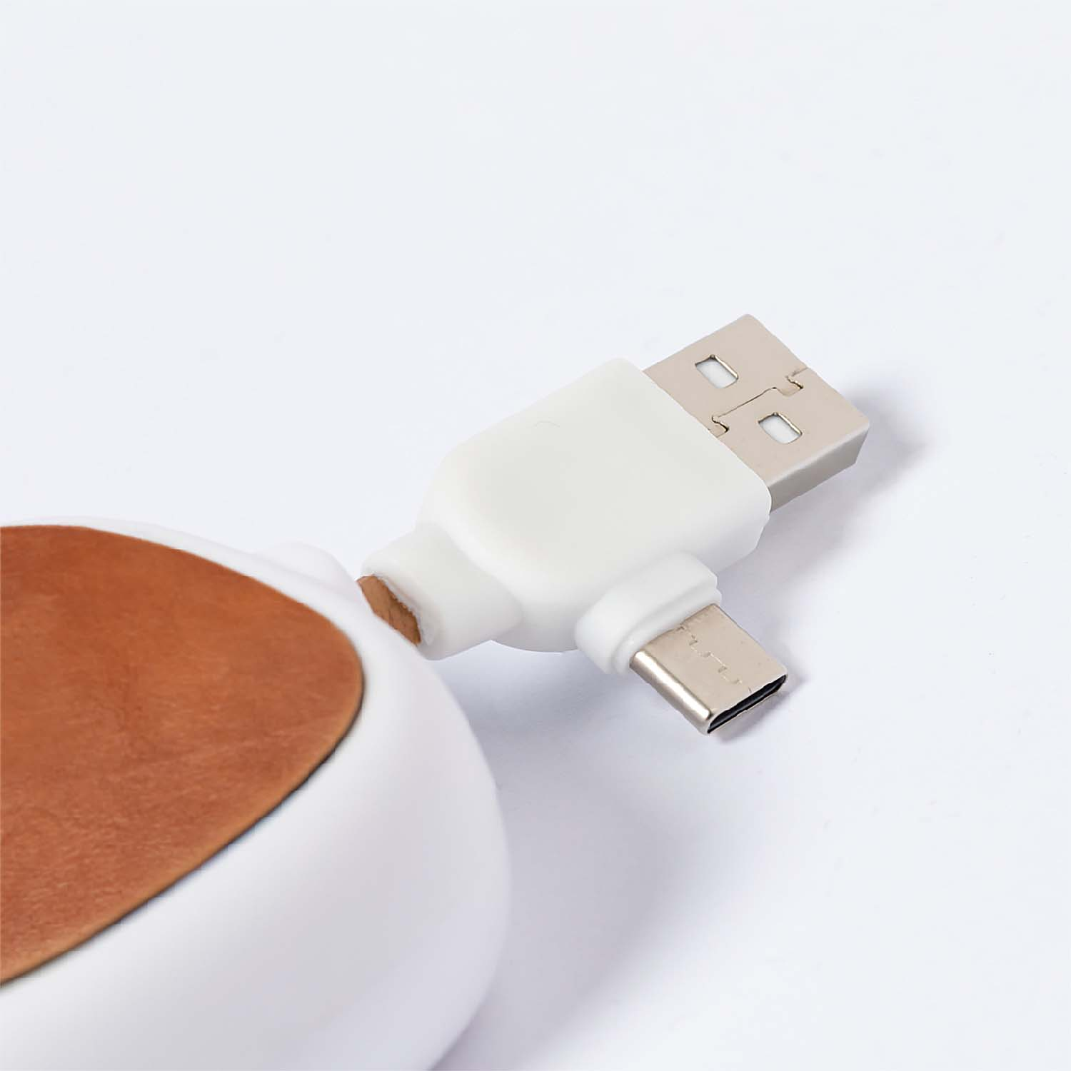 Un cavo di ricarica bianco con connettori USB-A e USB-C su sfondo bianco.