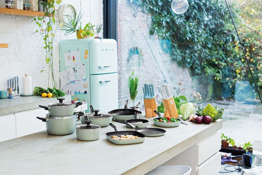 A kitchen with a mint fridge, cookware, and fresh vegetables.