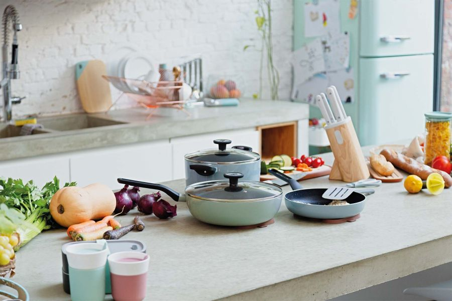 Kitchen counter with cookware, vegetables, and bread. Mint green fridge.