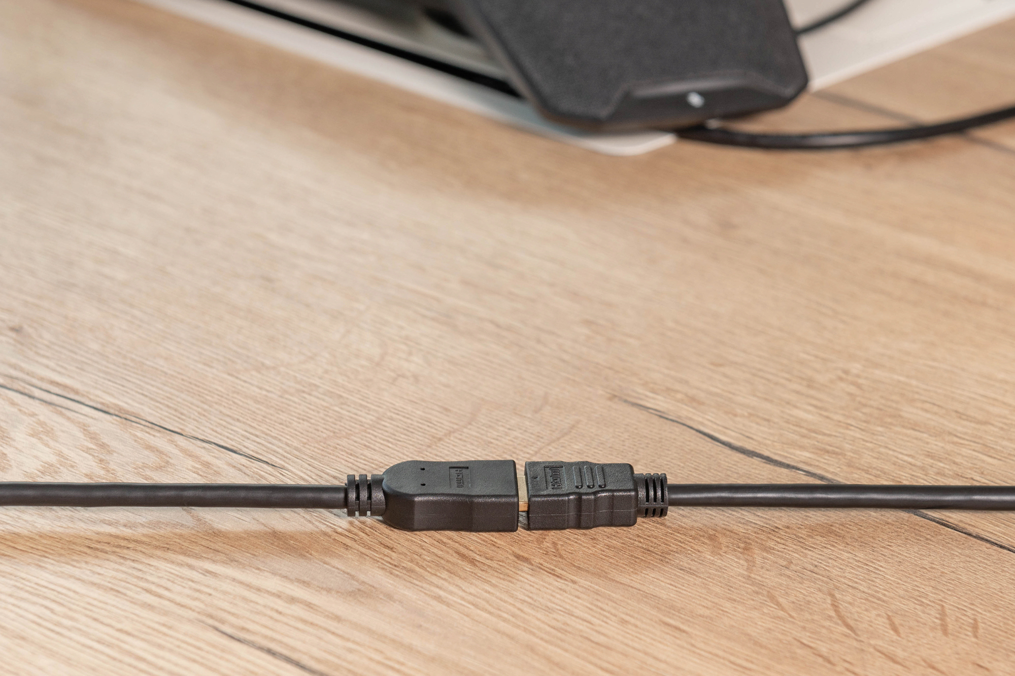 Deux adaptateurs de câble HDMI noirs sont connectés sur une table en bois.