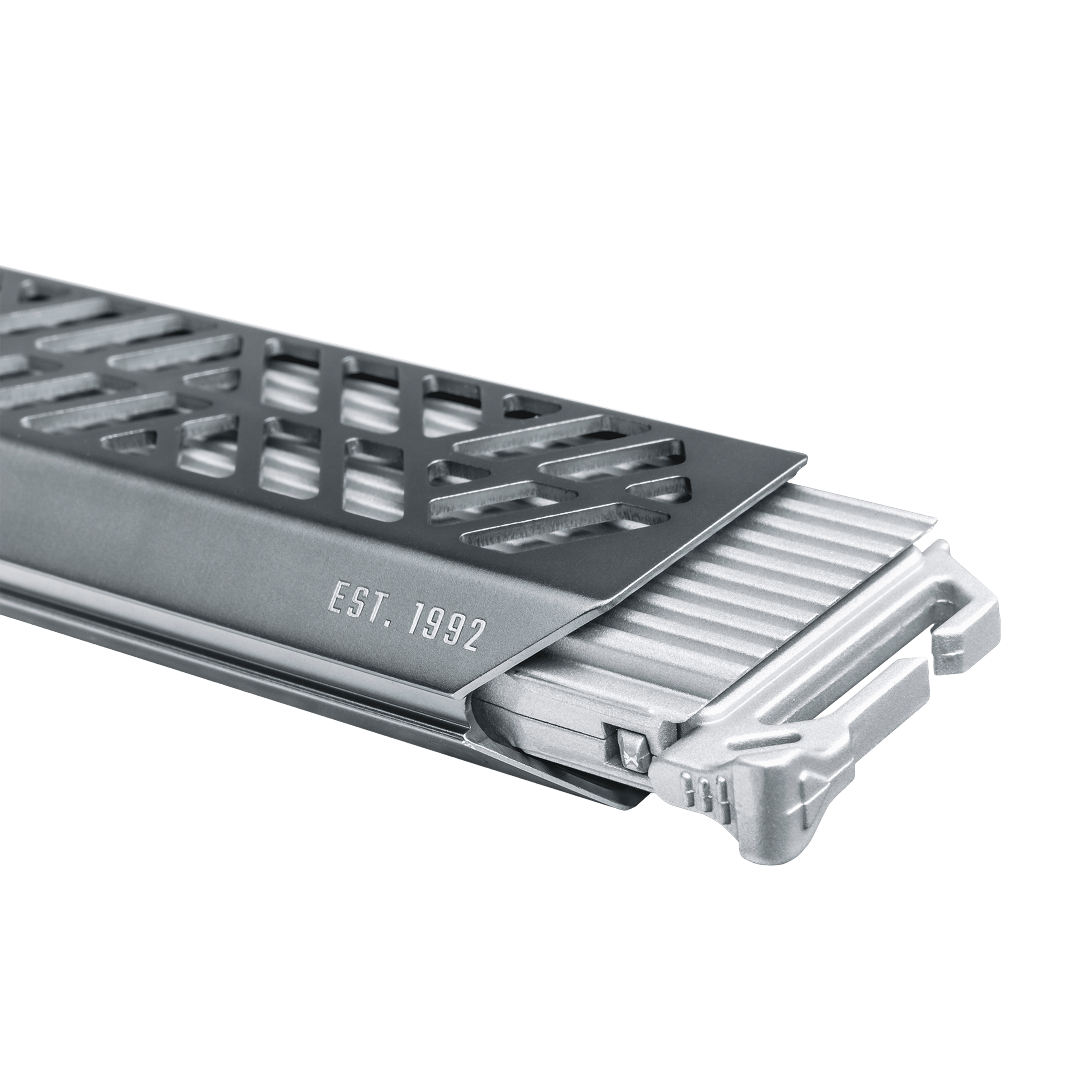 Grauer Metallgrill mit geometrischem Muster und eingraviertem Text.