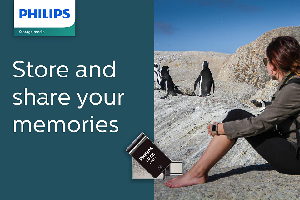 Eine Frau sitzt am Felsen und schaut Pinguine an. Philips USB-Stick.