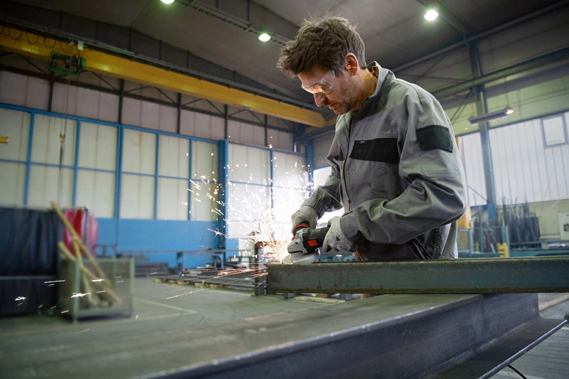Ein Mann schleift Metall in einer Werkstatt, Funken fliegen.