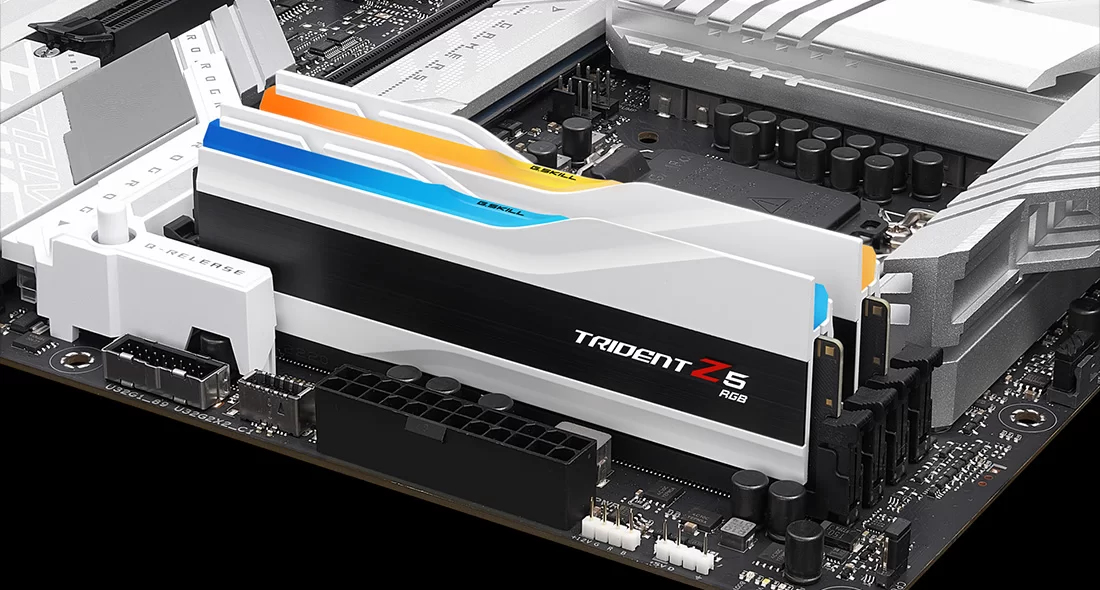 Deux modules RAM blancs aux accents orange et bleu sur une carte mère.