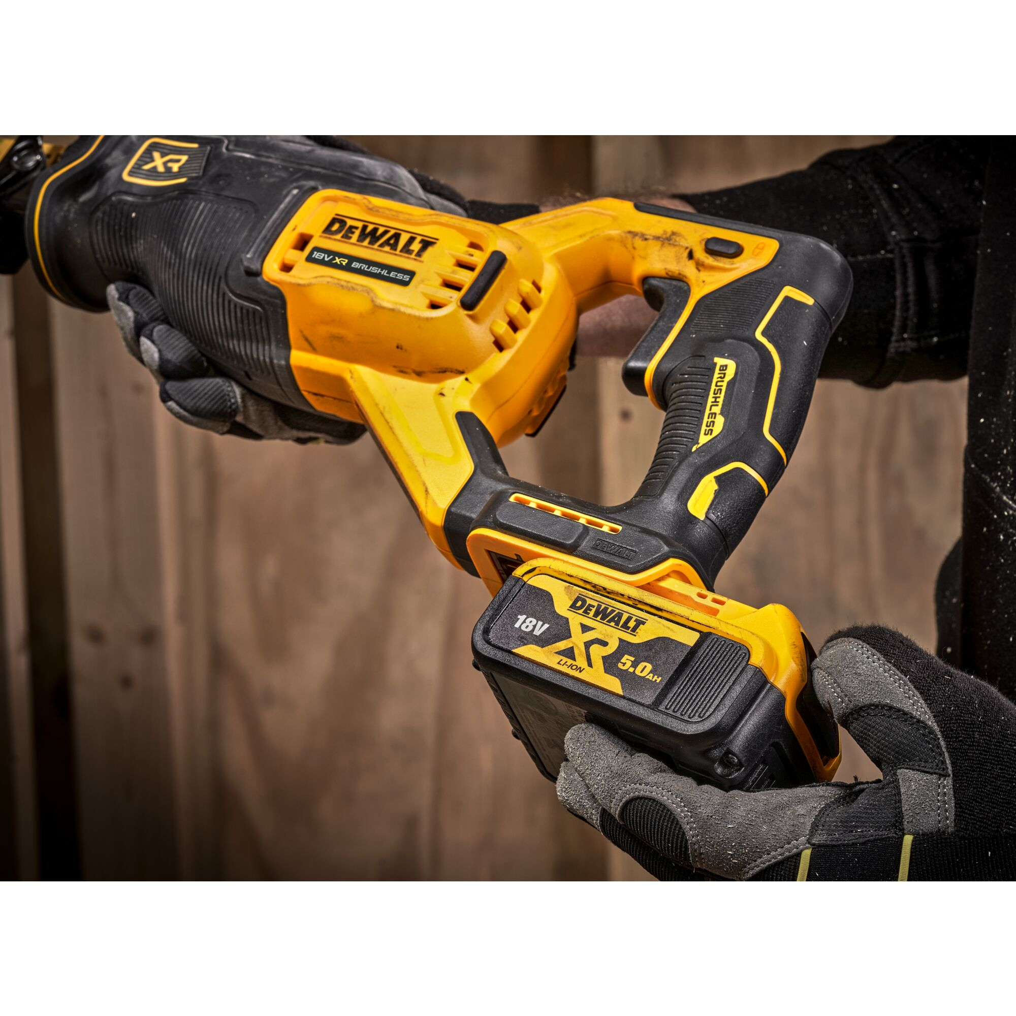 Gelbe und schwarze Dewalt Stichsäge mit 18V Akku, gehalten von Händen mit Handschuhen.