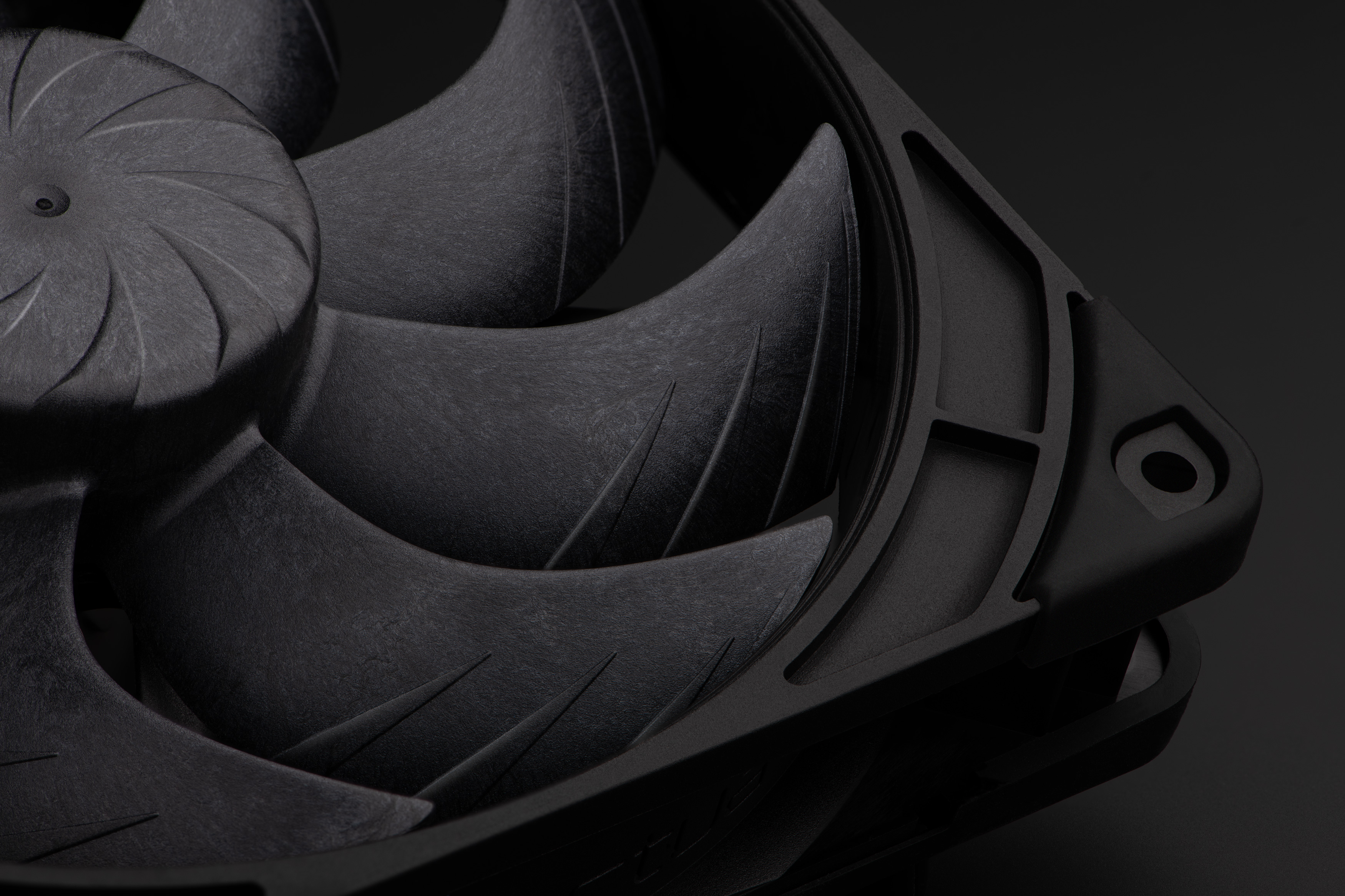 Close-up of a black computer fan with curved blades and textured surface on a dark background.