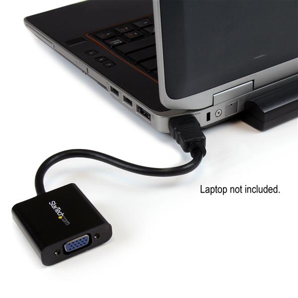 Un adaptador negro conecta una laptop a un puerto VGA. Laptop no incluida.