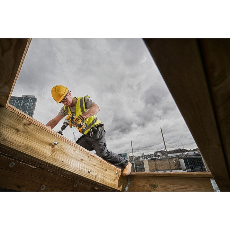 Bouwvakker met boormachine op houten constructie.