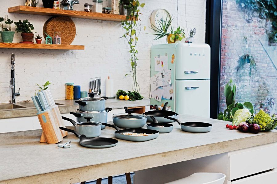 A kitchen scene with cookware, a refrigerator, and produce on the counter.