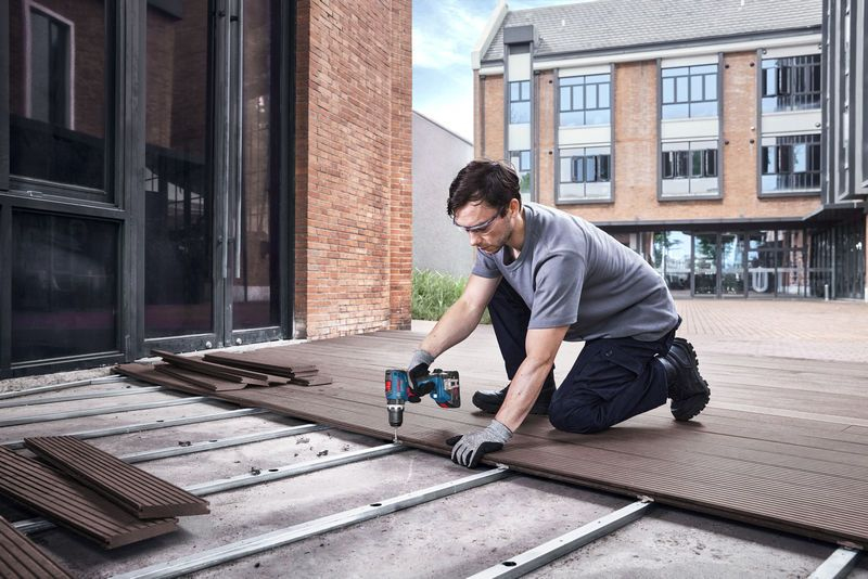 Mann schraubt Holzdiele auf Metallträger, Bau mit Werkzeug