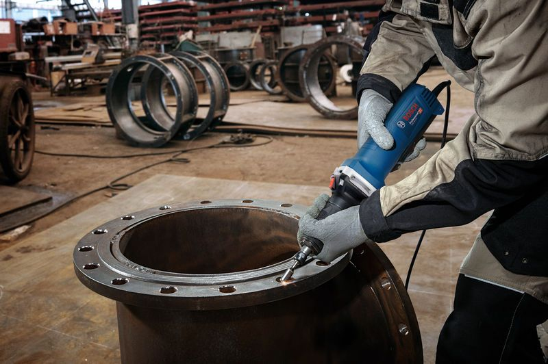 Bir işçi, mavi bir Bosch aletiyle metal flanş açıklığını zımparalıyor.