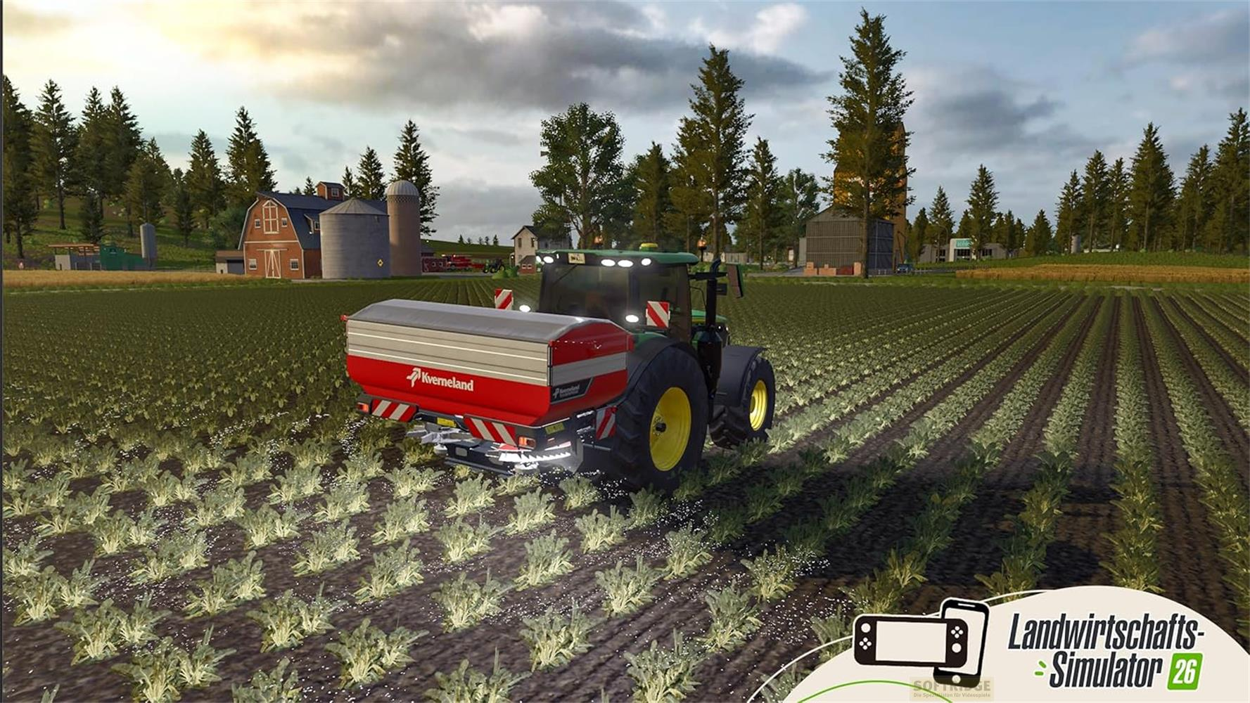 Ein grüner Traktor mit einem roten Anhänger fährt über ein Feld.