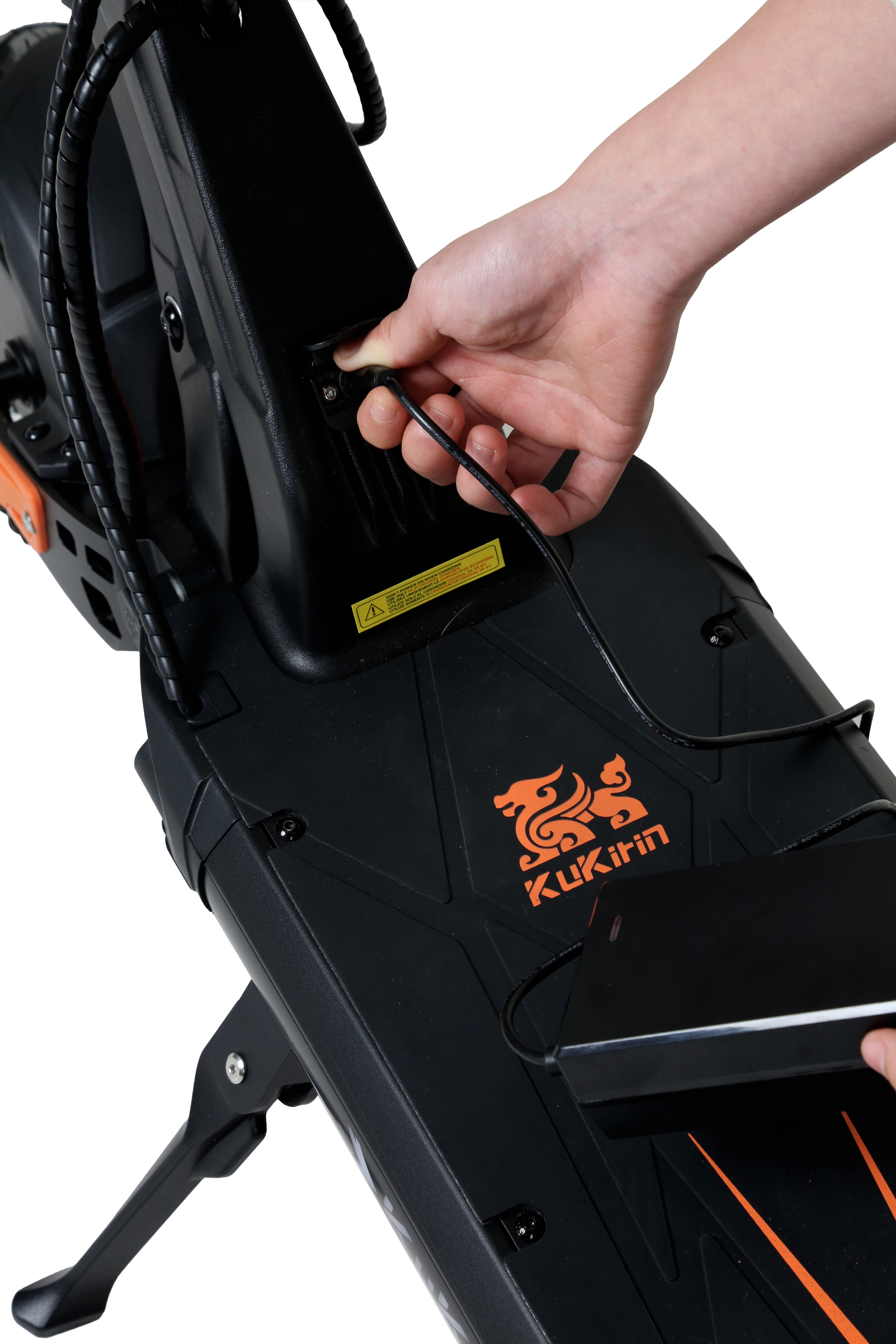 Eine Hand steckt ein Ladekabel in einen schwarzen E-Scooter mit orangefarbenem Logo.