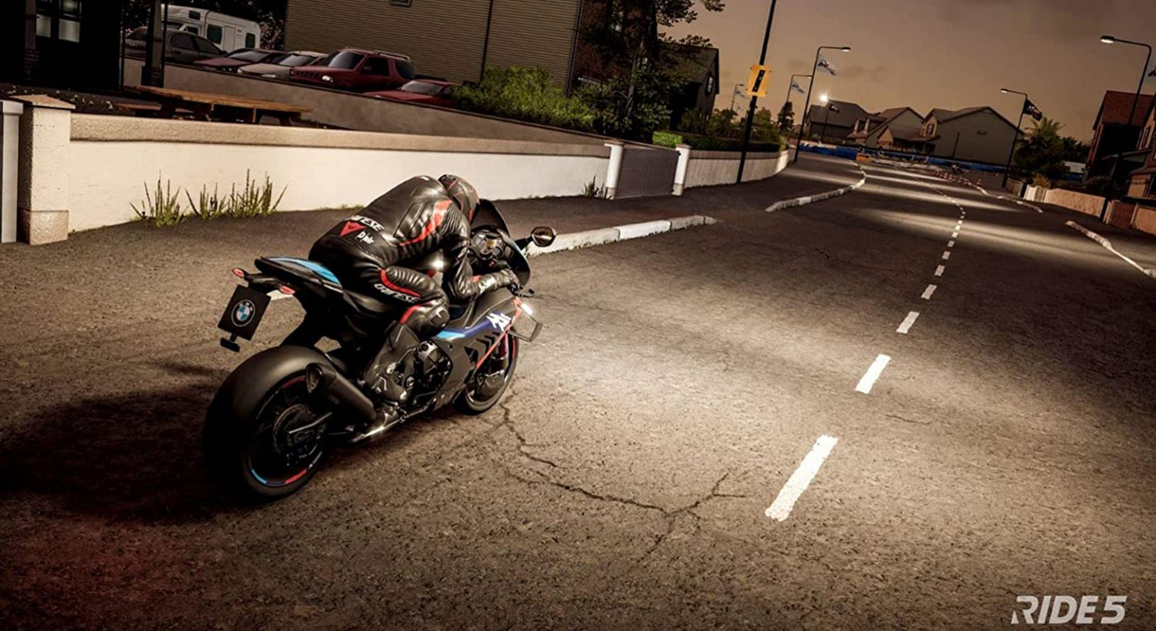 Un motociclista in tenuta nera e rossa guida una BMW nera su strada scura e fessurata.