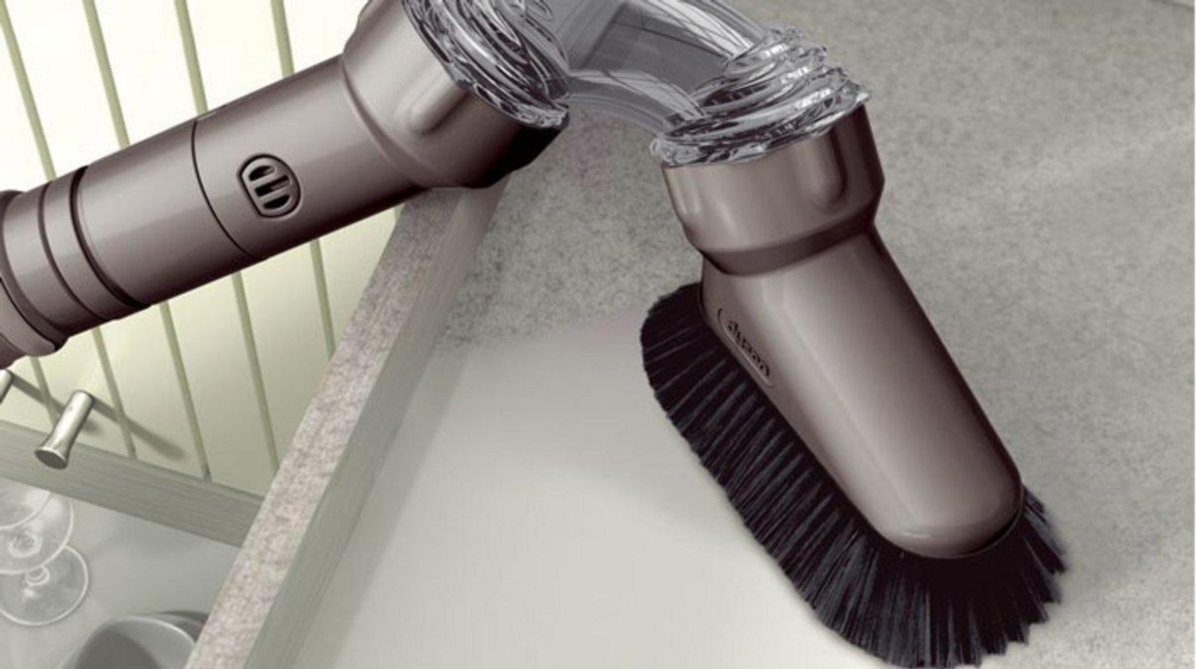 Un accessorio per aspirapolvere grigio con spazzole pulisce una superficie grigia.