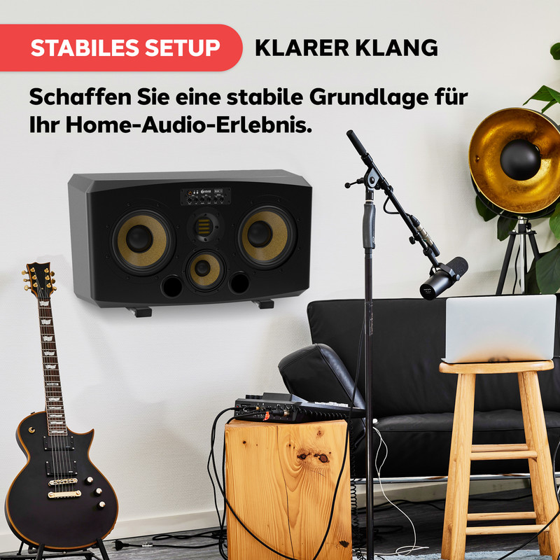 Schwarzer Studiomonitor an Wand, Gitarre, Mischpult, Mikrofonständer, Laptop.
