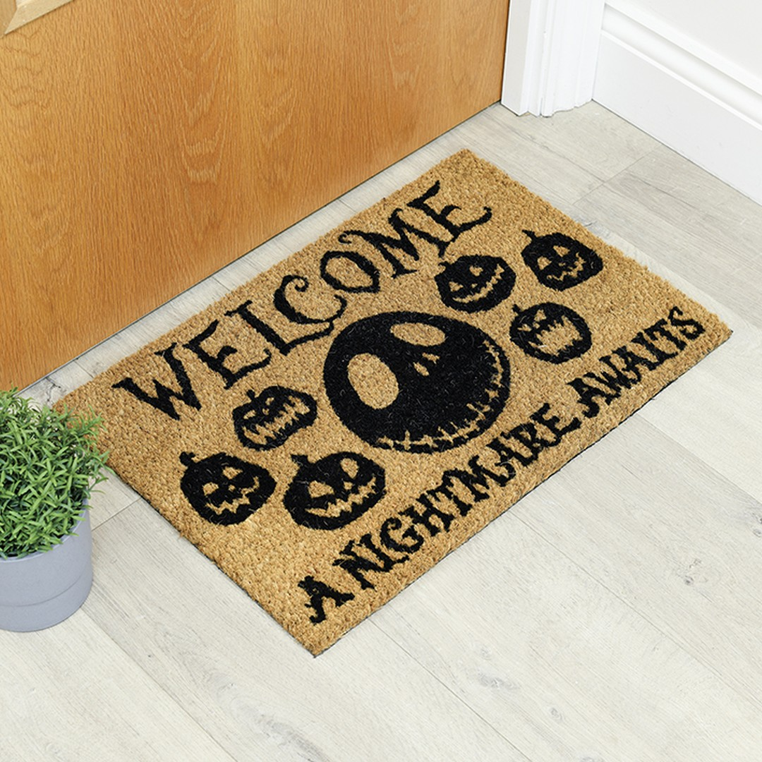 Felpudo de bienvenida con calabazas y texto "A Nightmare Awaits".
