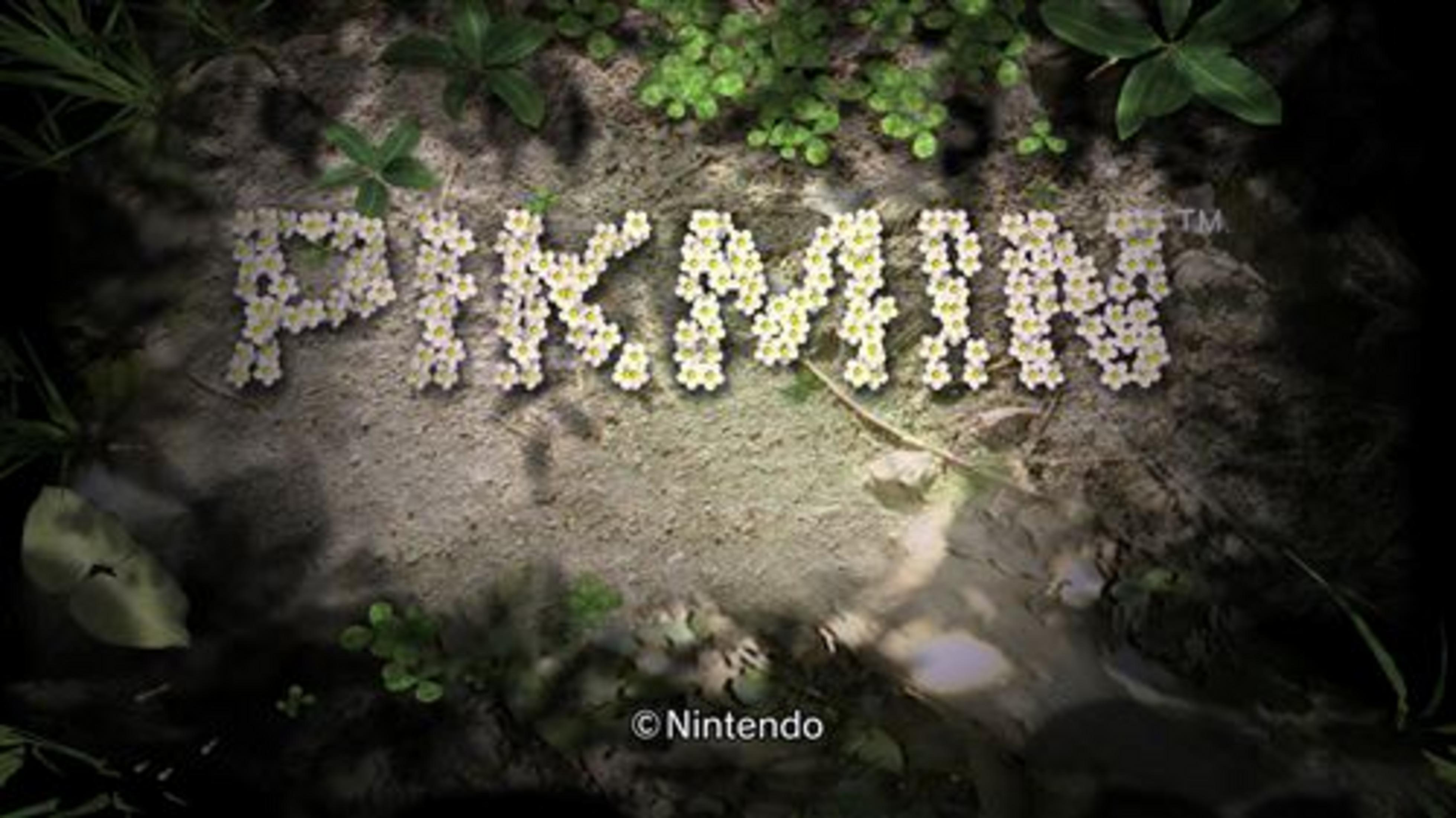 La parola Pikmin formata da fiori bianchi su una superficie di pietra, con piante verdi intorno.