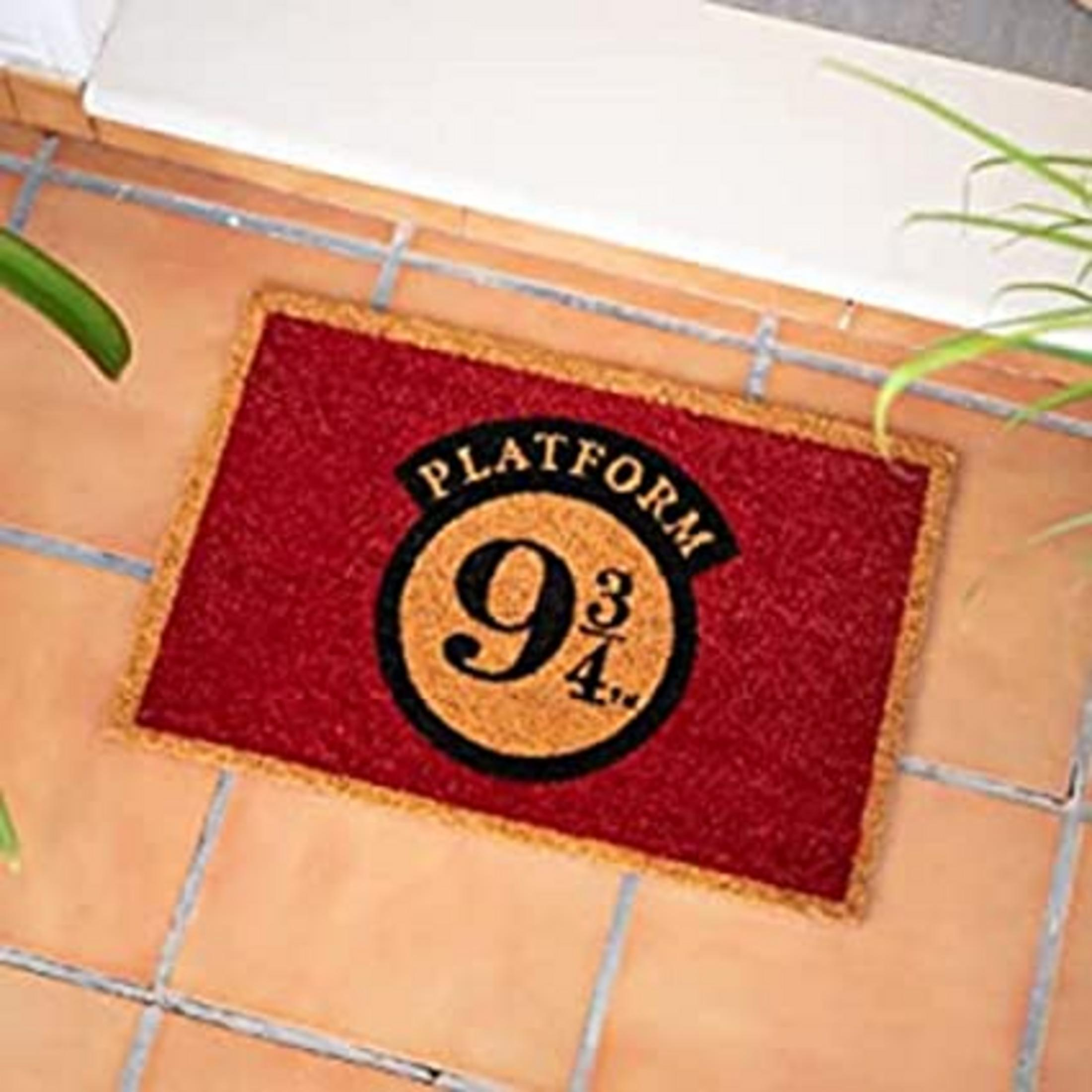 Czerwona wycieraczka z czarno-złotym logo "Platform 9 3/4".
