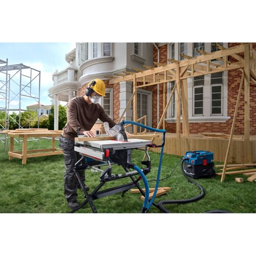 Mann sägt Holz auf Baustelle mit Kreissäge vor Haus.