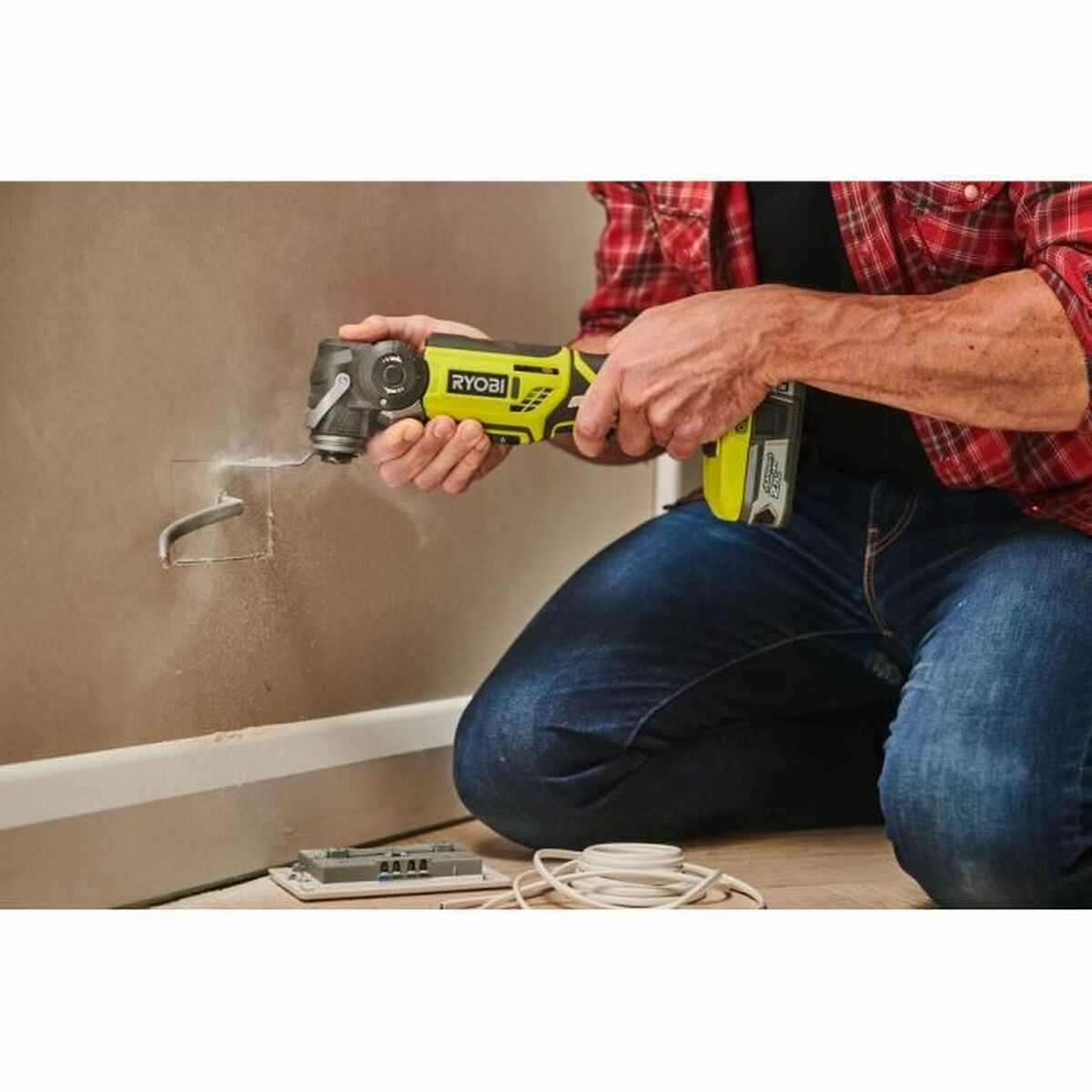 Mann mit gelbem Werkzeug schneidet Loch in Wand, blauer Jeans, Holzboden.