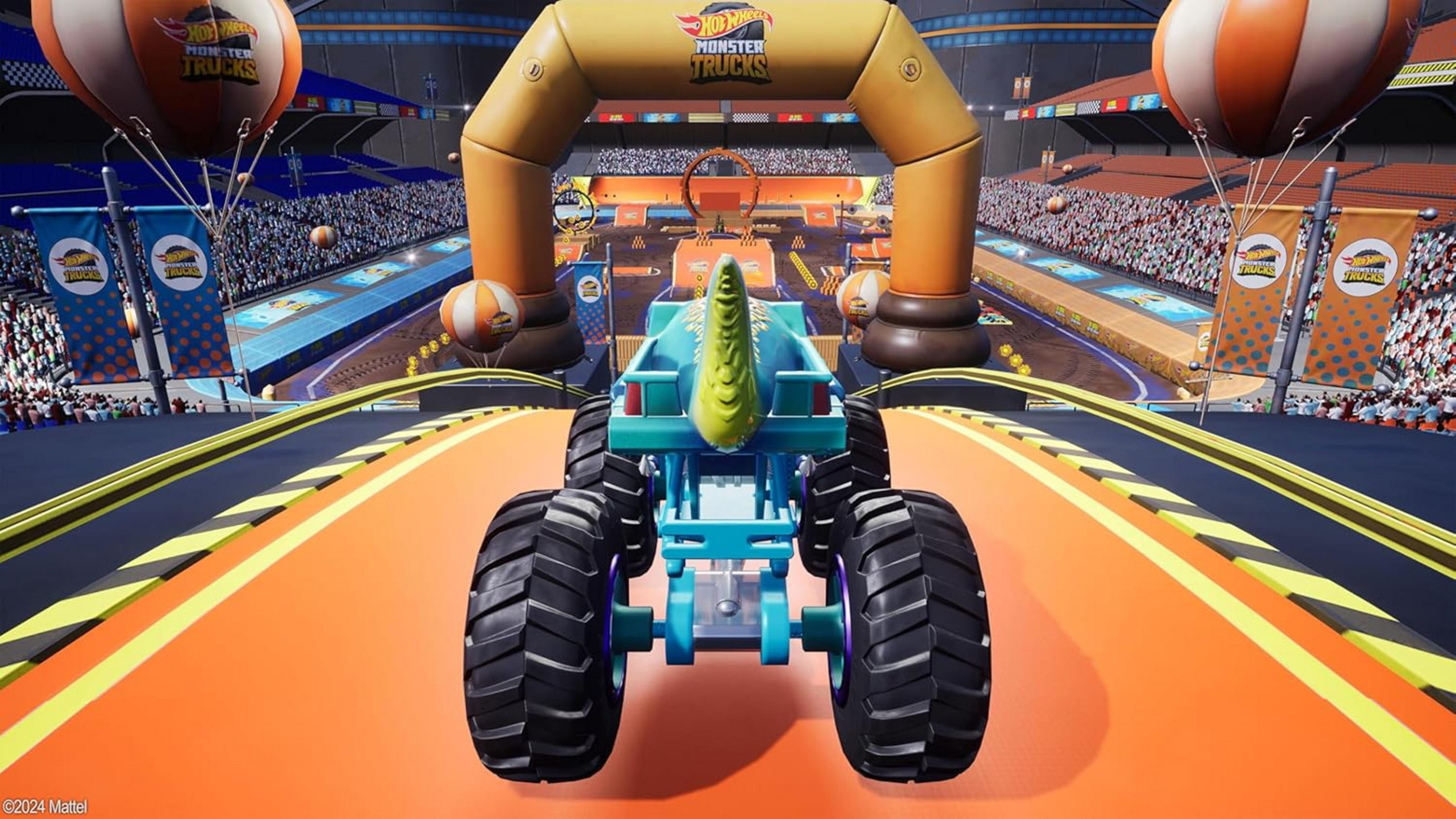 Un monster truck blu con design da dinosauro si trova sotto un arco giallo in uno stadio.