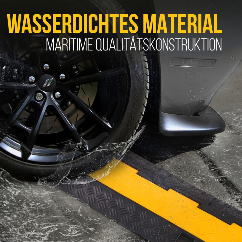 Ein schwarzes Auto fährt über eine gelb-schwarze Rampe, Wasser spritzt.