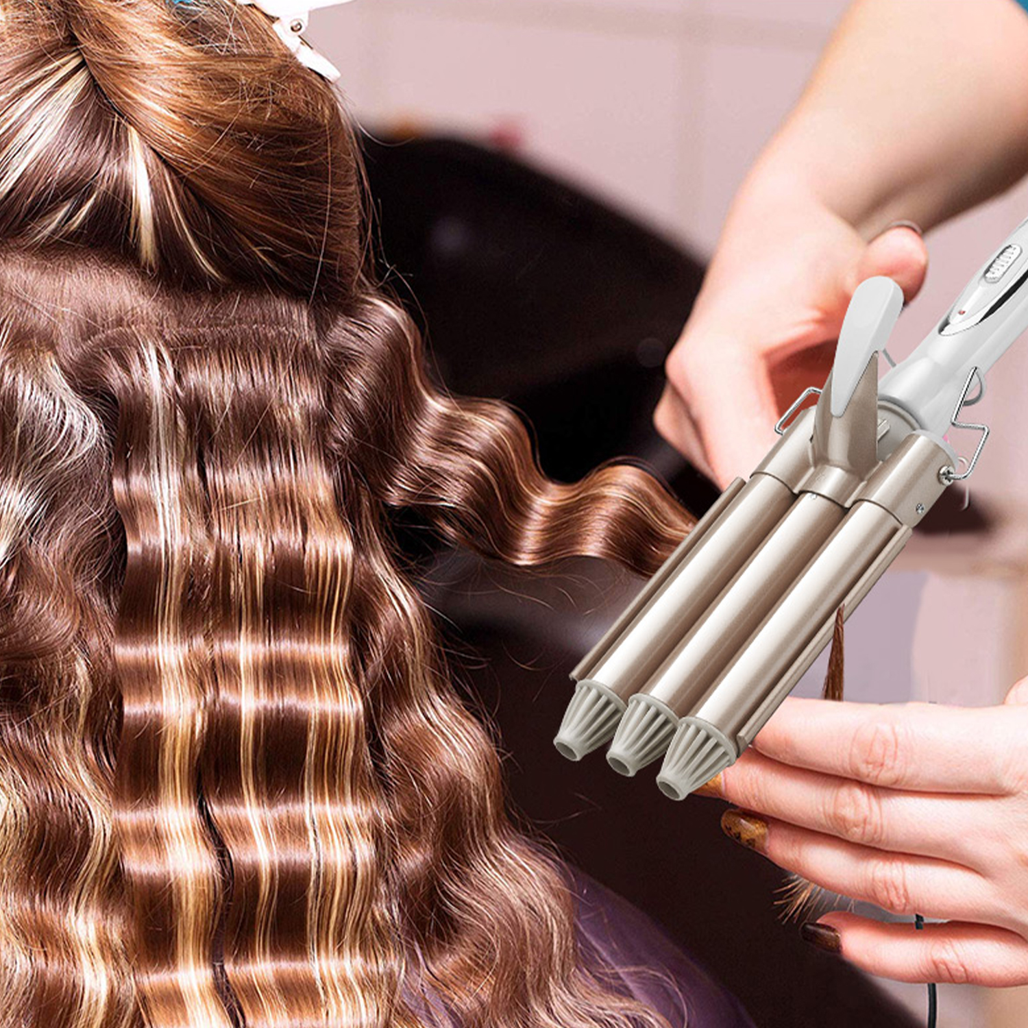 Estilista usa un rizador triple en el cabello castaño de una persona con reflejos rubios.