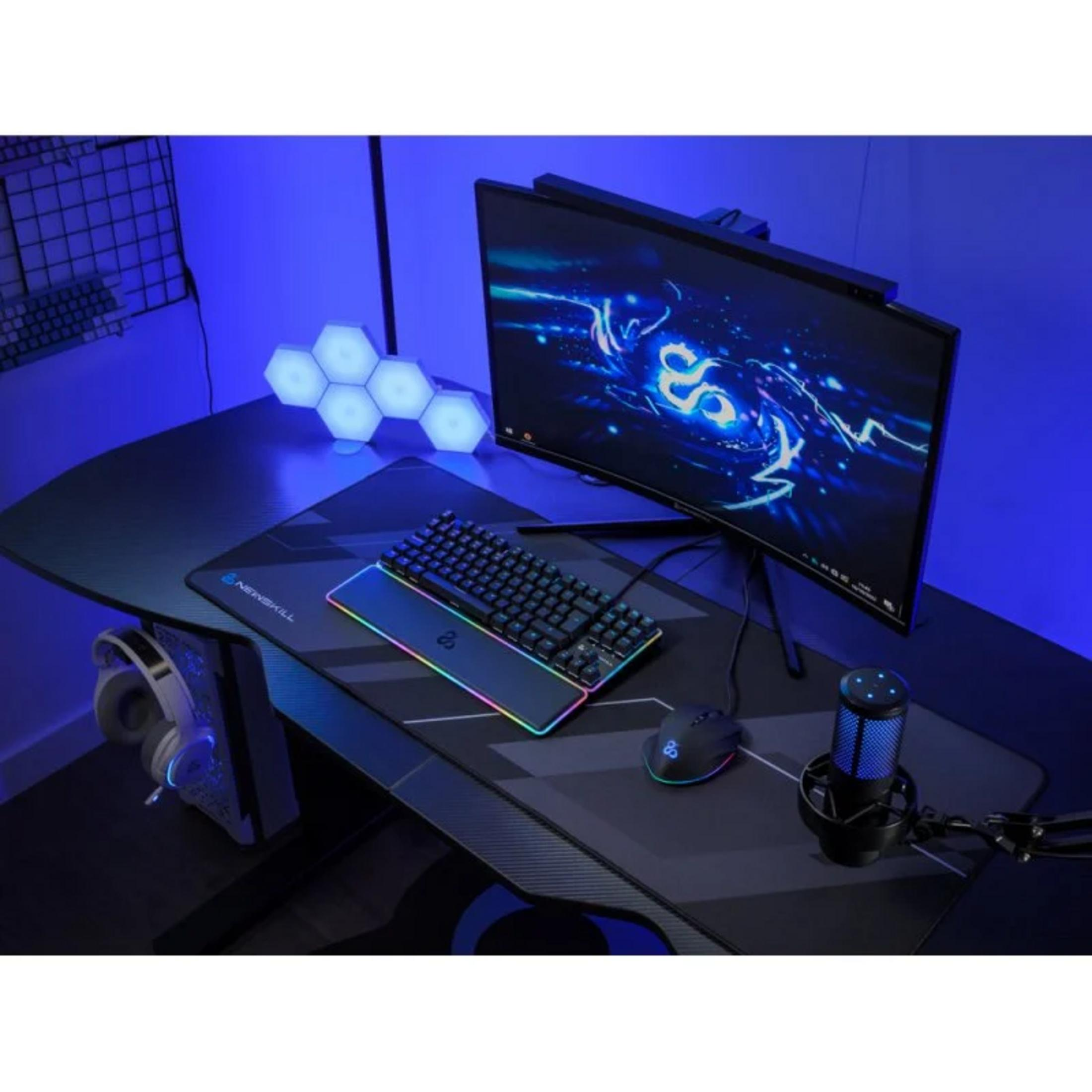 Un escritorio para juegos con monitor, teclado, ratón, micrófono y auriculares.
