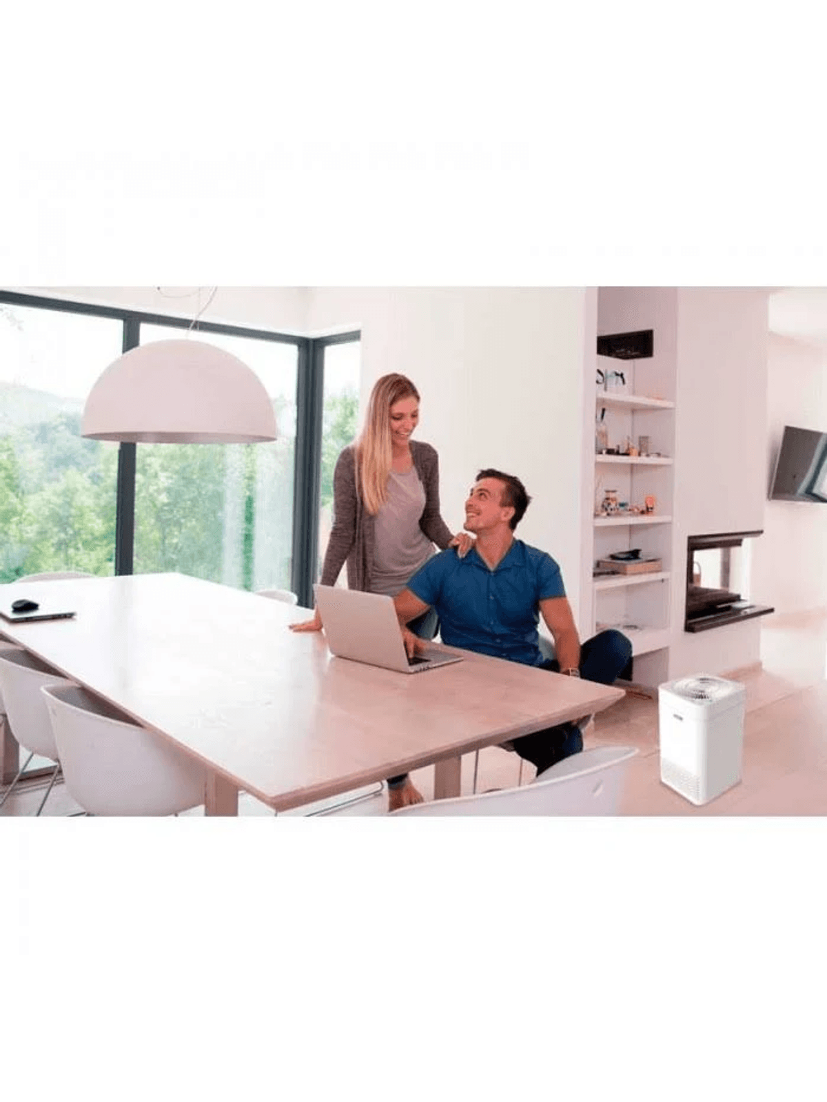 Hombre y mujer en mesa con portátil, purificador de aire delante.