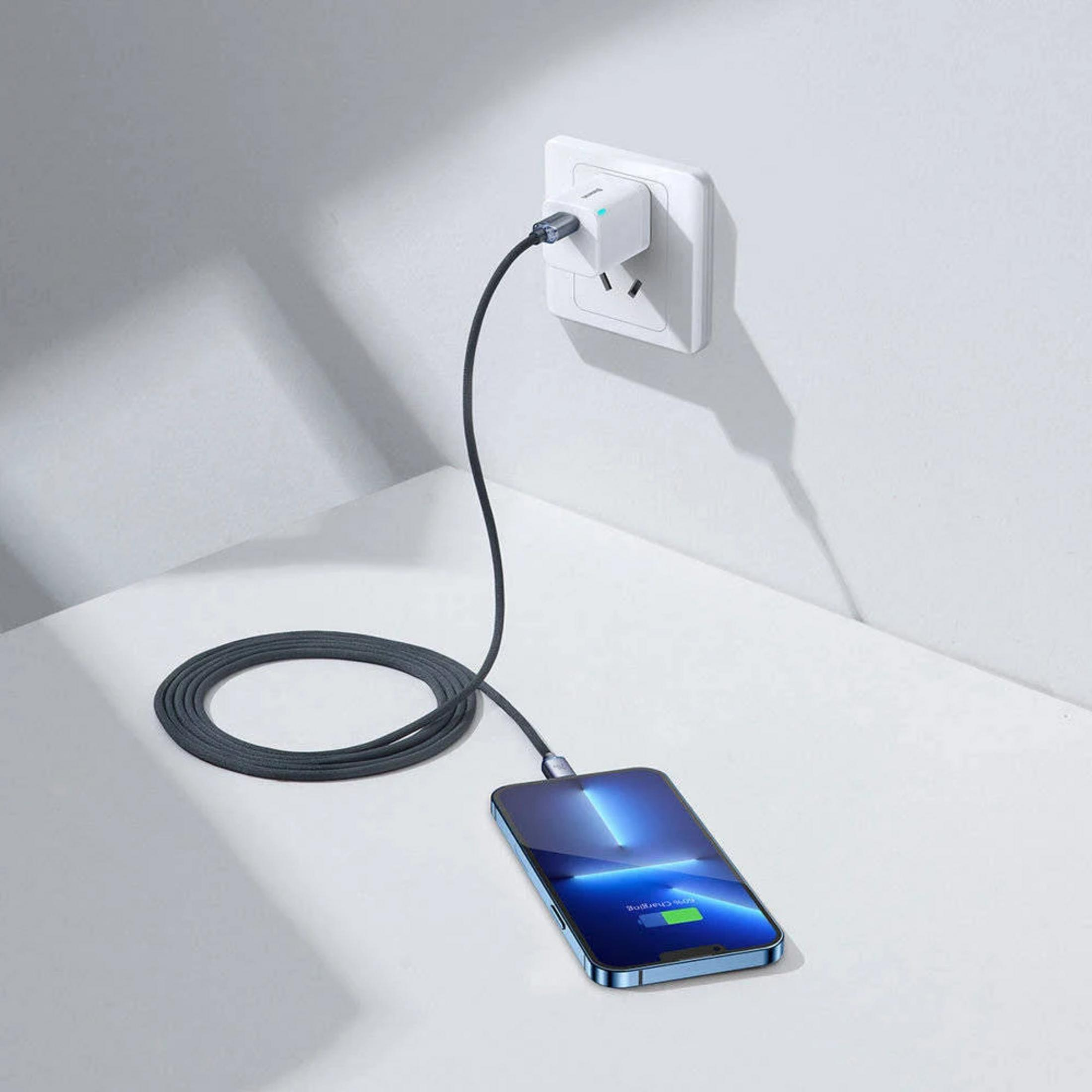 Een telefoon laadt op via een stekkerdoos en een zwart snoer aan de muur.