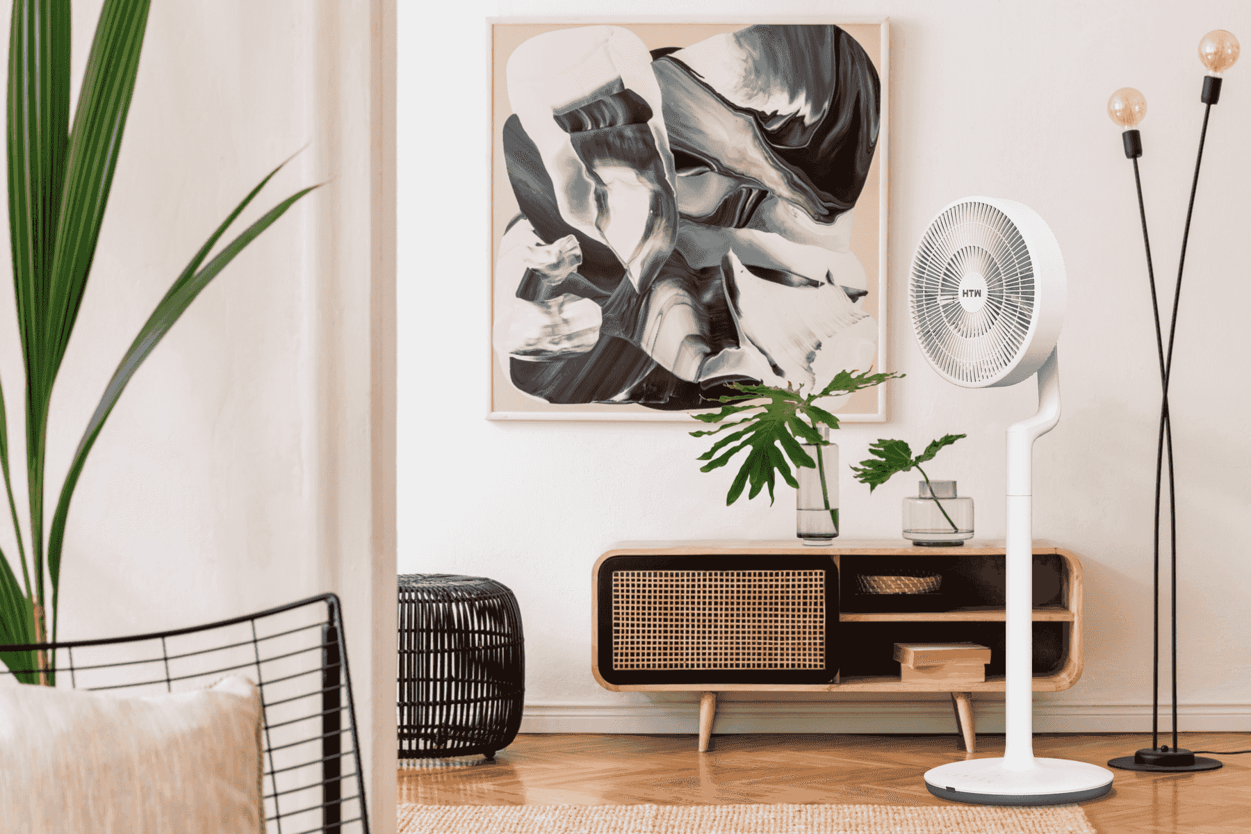 Un ventilador blanco junto a un mueble de madera con arte y plantas.